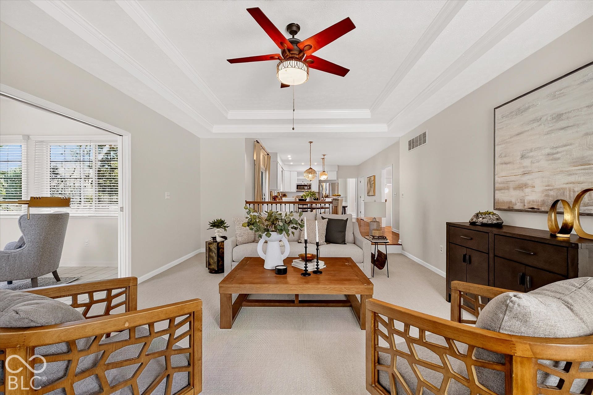 Tray ceiling with a decorative ceiling fan, light-toned wall paint, and a wood-finish coffee table