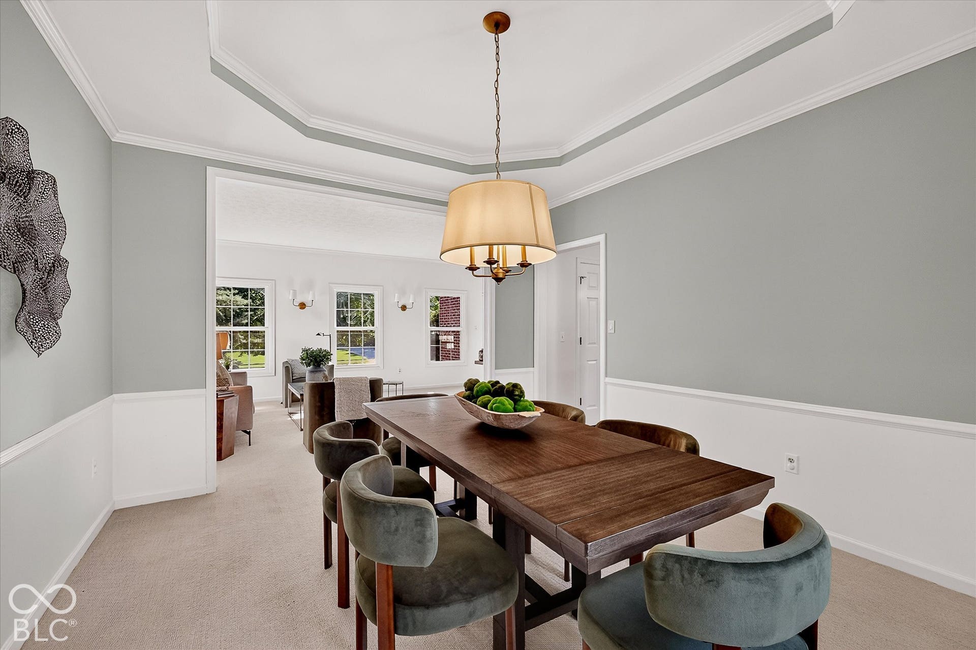 Tray ceiling with crown molding, chandelier, chair rail, and wall sconces
