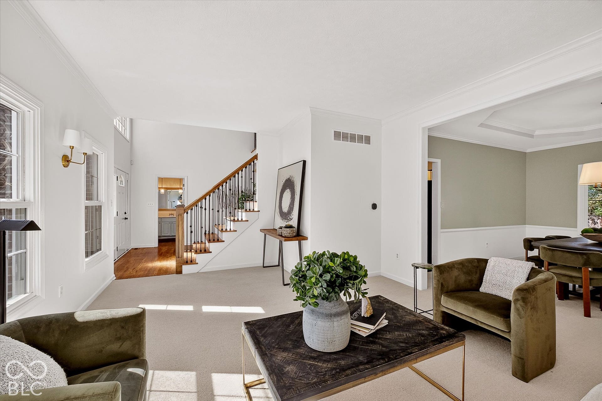 Two-story foyer with wood-finish flooring, staircase with dark wood-finish handrail, and white balusters