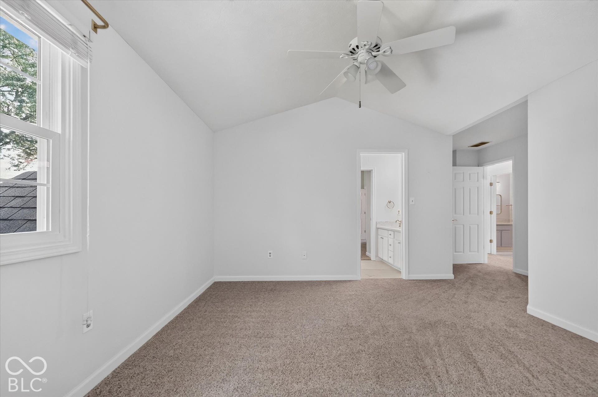 Vaulted ceiling, ceiling fan, window with natural light, carpeted flooring, and white painted walls