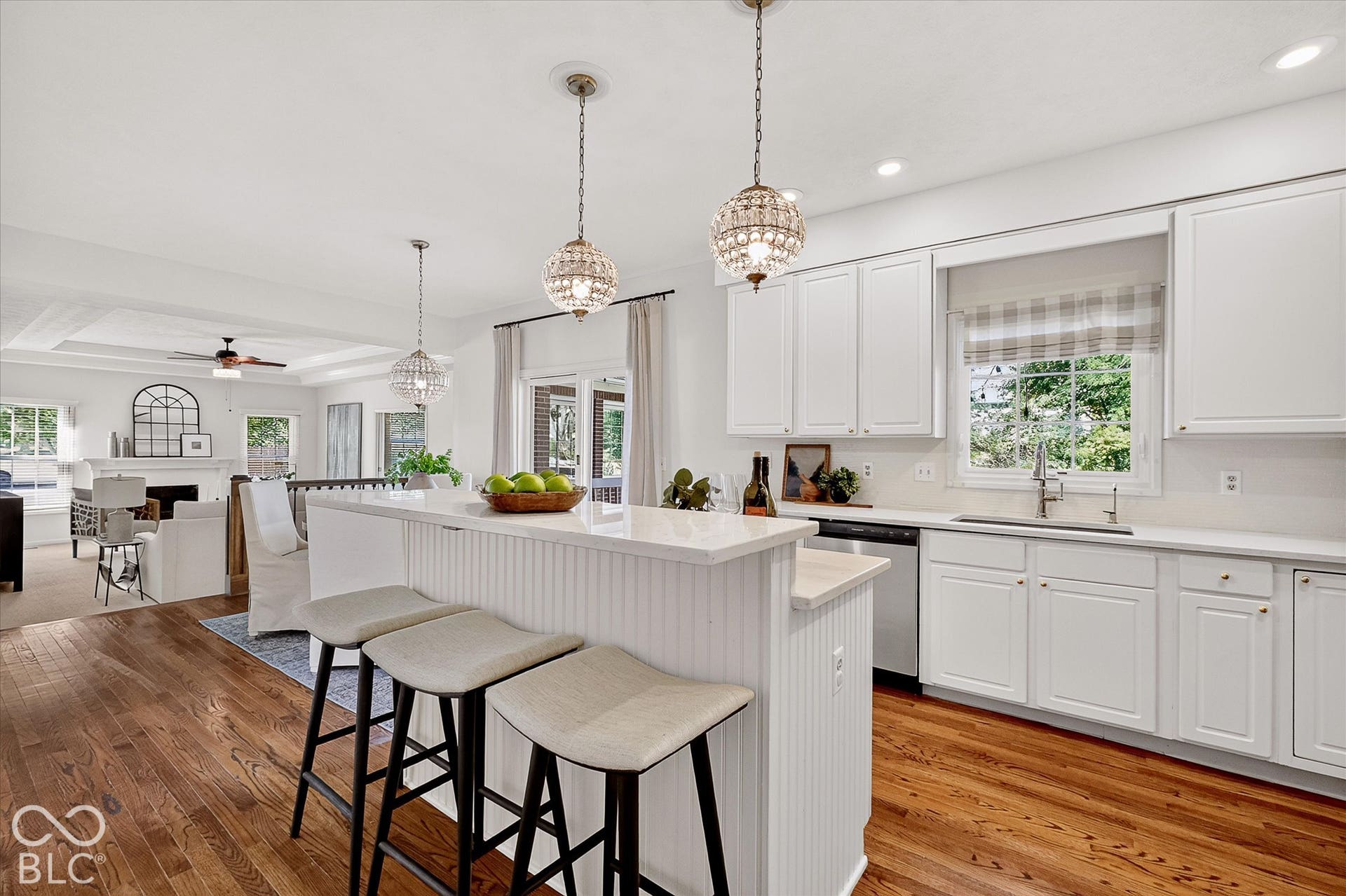 Open-concept kitchen featuring white cabinetry, light countertops, stainless steel appliances, and wood-finish flooring