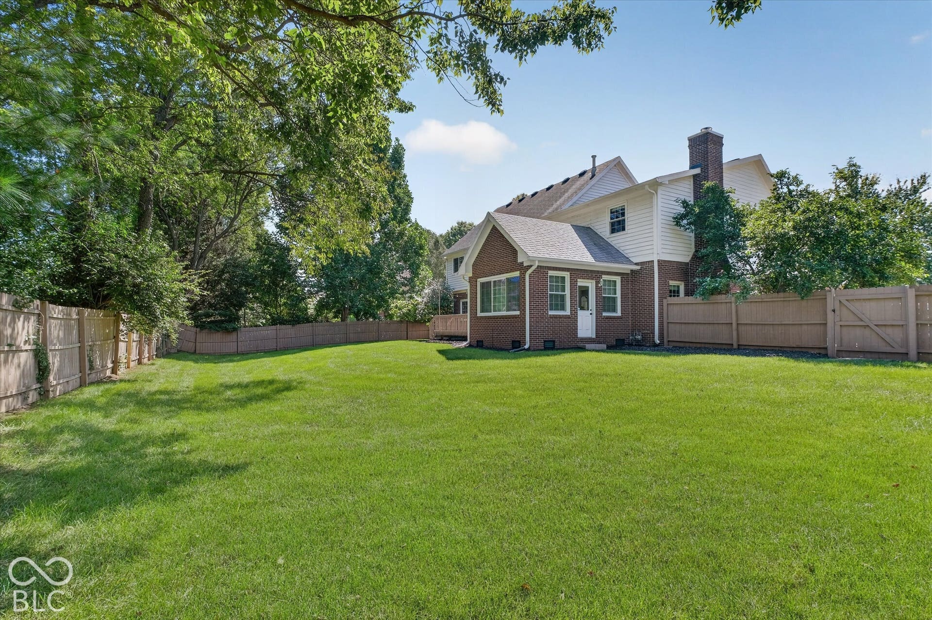 Expansive lawn with mature trees and a wood privacy fence