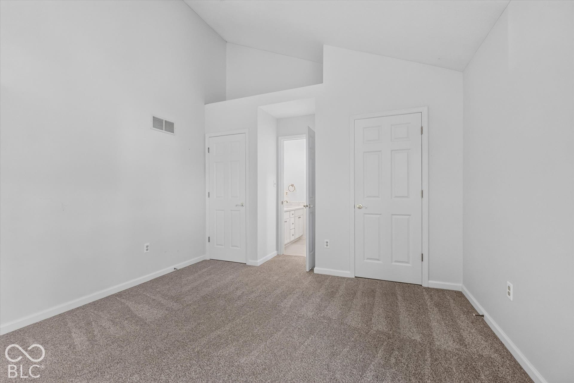 Vaulted ceiling with a neutral carpet flooring