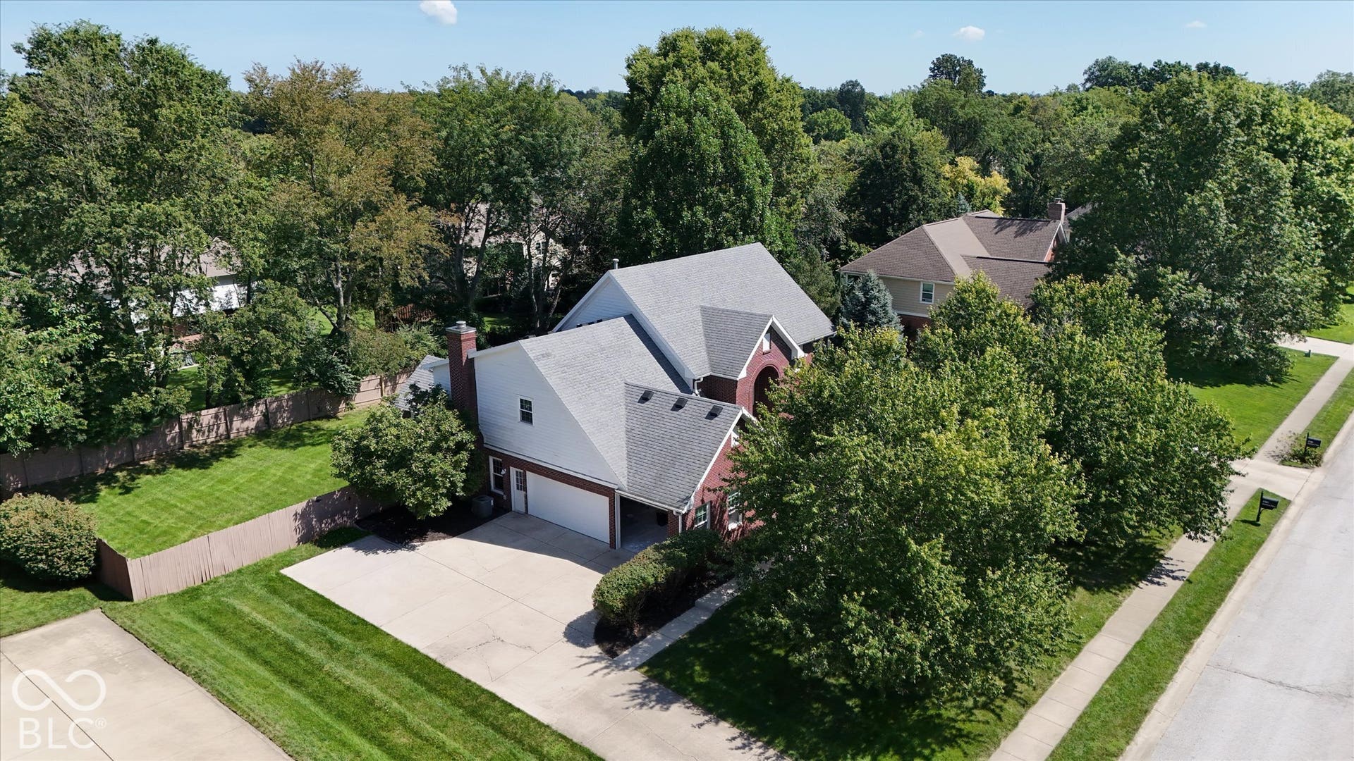 Expansive residential property featuring a multi-level roofline, attached garage, concrete driveway, and mature landscaping