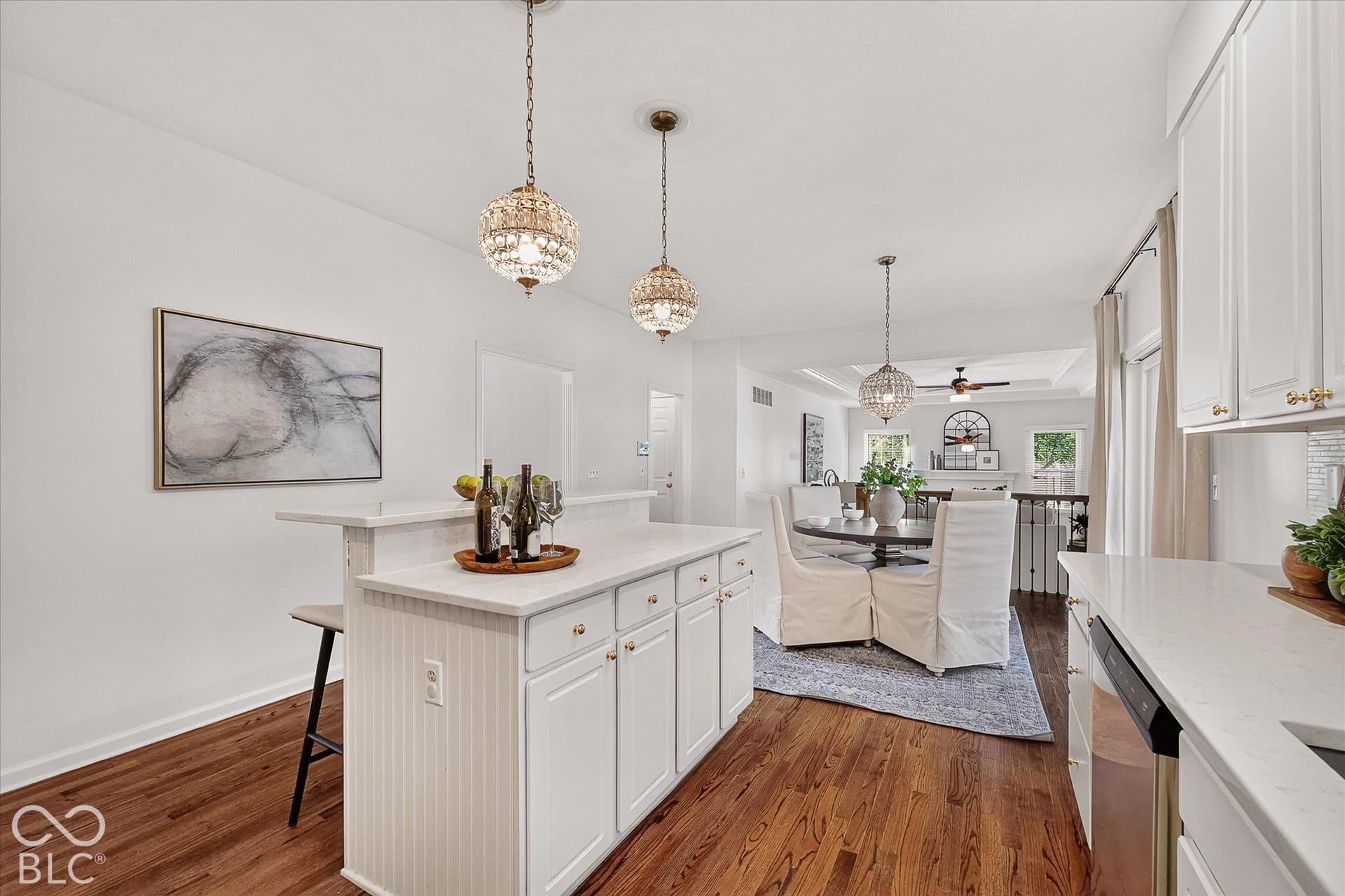 White cabinetry, wood-finish flooring, white countertops, built-in island, and decorative pendant lighting