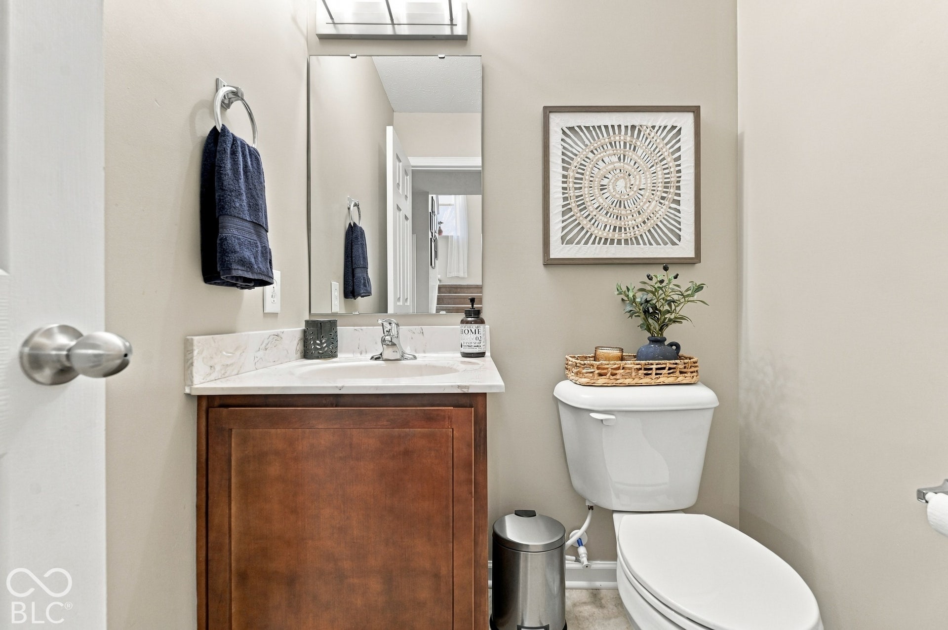 White vanity with wood-finish cabinetry, light-toned countertop, and integrated sink