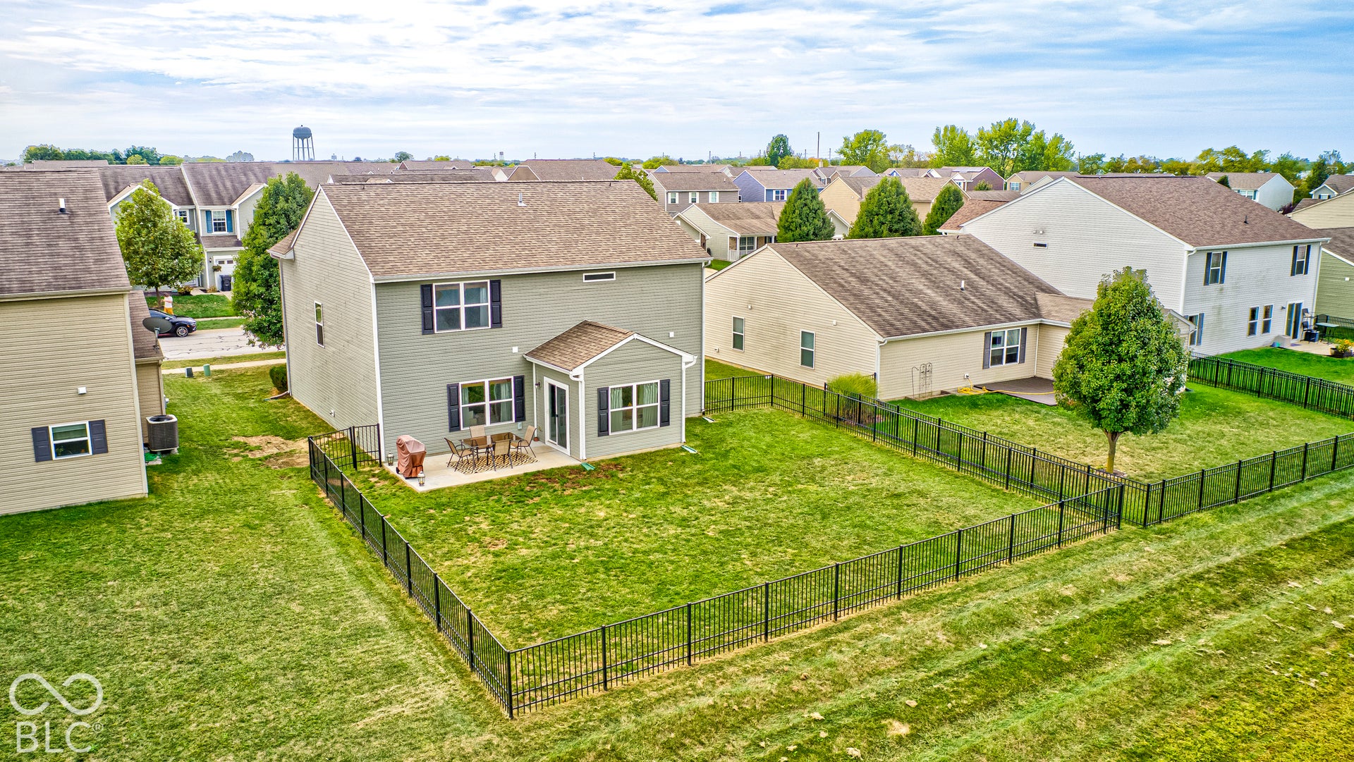 Expansive backyard featuring a manicured lawn, established tree, and full perimeter fencing