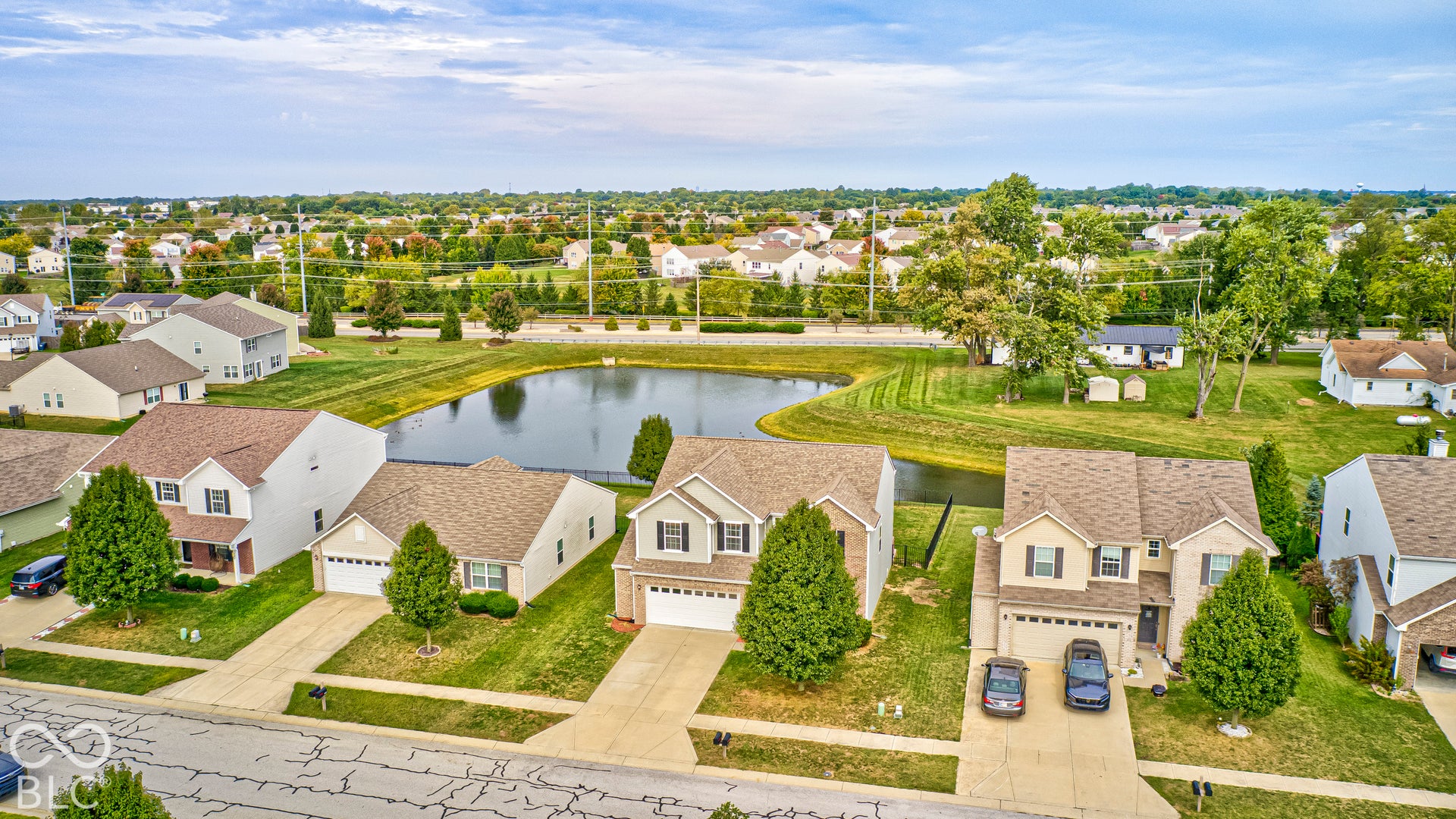 Pond-front property featuring a two-story residence with an attached two-car garage, concrete driveway, and established landscaping