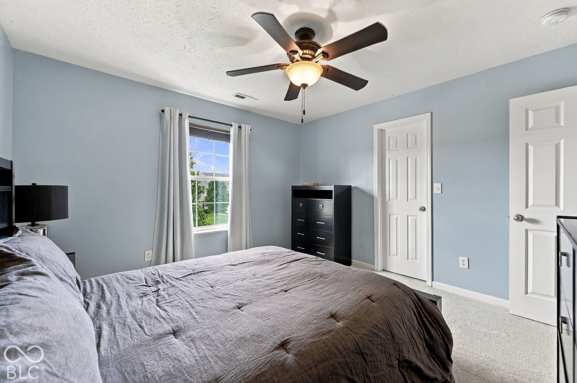 Room featuring a ceiling fan with integrated lighting, a window with exterior visibility, light-toned carpeting, and a six-panel interior door