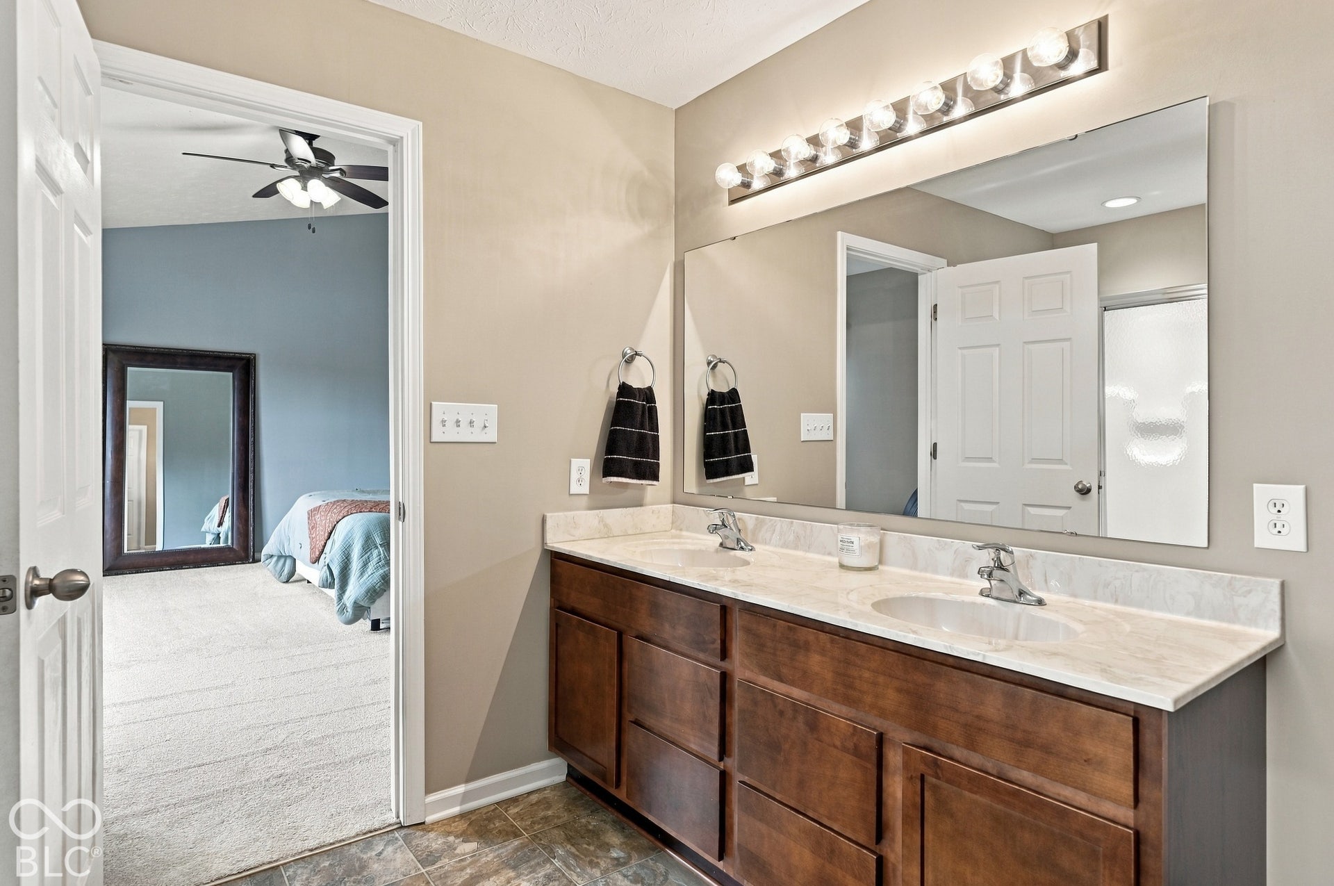 Dual vanity with wood-finish cabinetry, light-toned countertop, and dual undermount sinks