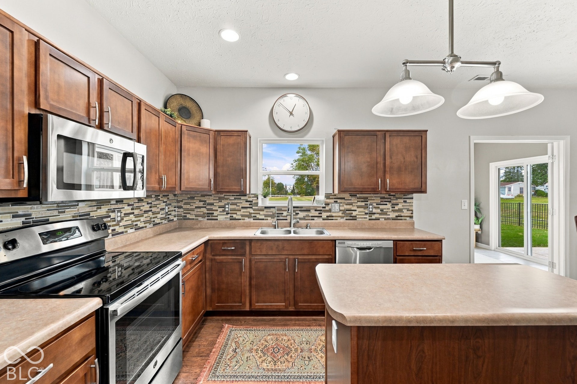 Kitchen featuring wood cabinetry, stainless steel appliances, mosaic tile backsplash, and a central island with countertop space
