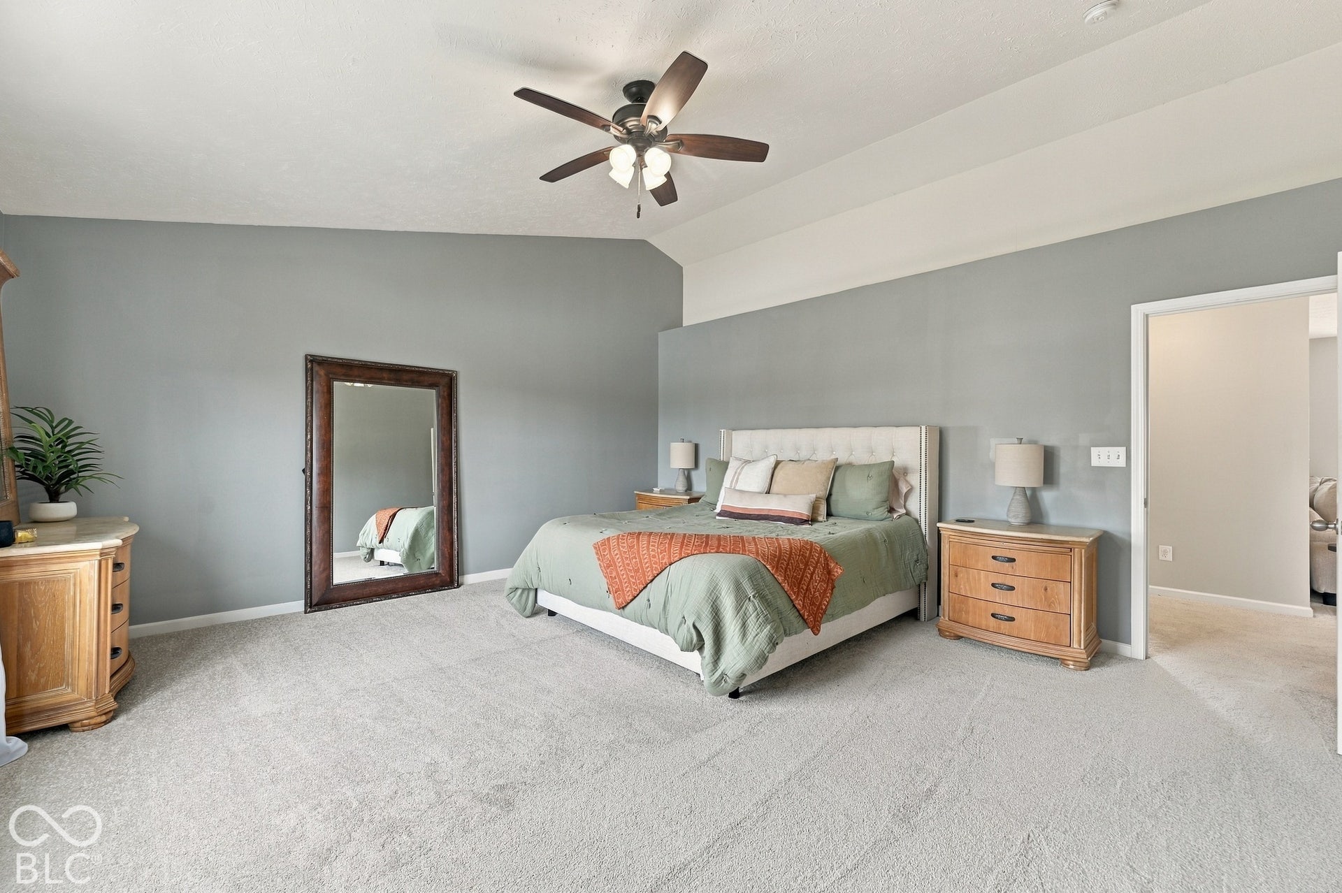 Carpeted room featuring a ceiling fan with light fixture and a vaulted ceiling