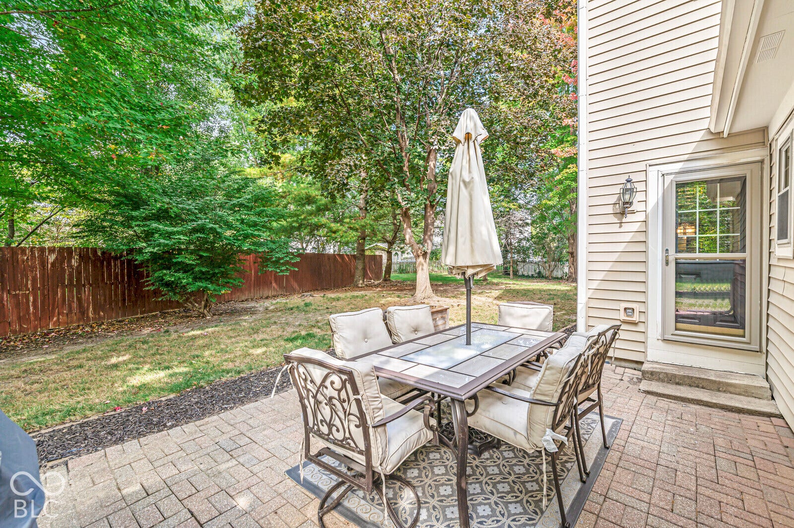Patio featuring brick paver flooring, exterior wall sconce, and a screen door entry