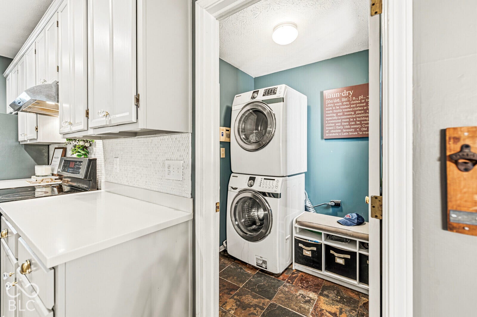 White upper and lower cabinetry, white solid surface countertop, white tile backsplash, and stainless steel range hood