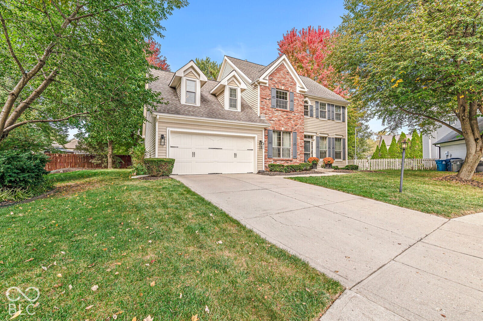 Two-story residence featuring brick and siding facade, dormer windows, attached garage, and a concrete driveway