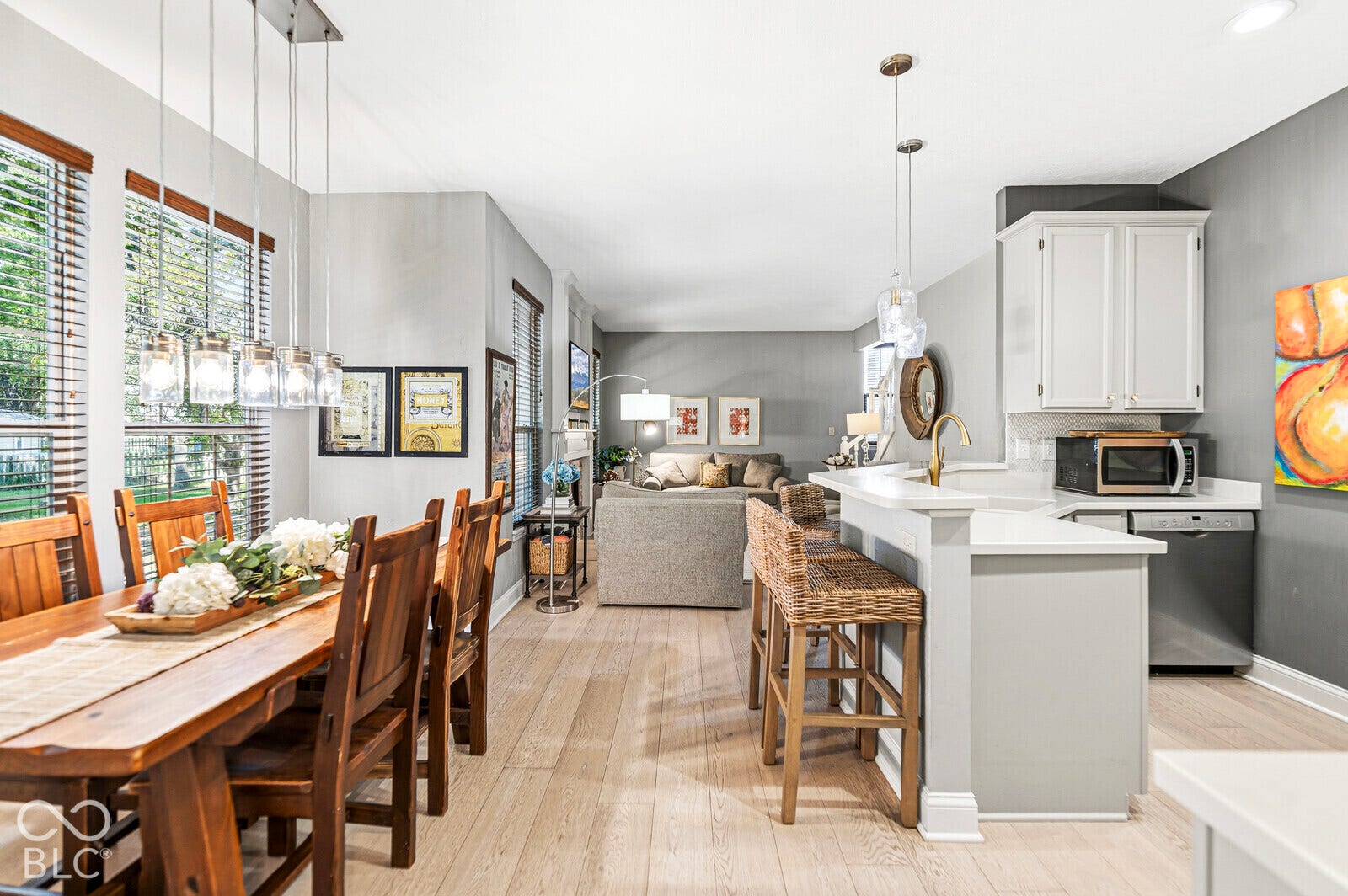 Hardwood-style flooring extends through the open concept living space, featuring a kitchen island with seating, pendant lighting, and multiple windows