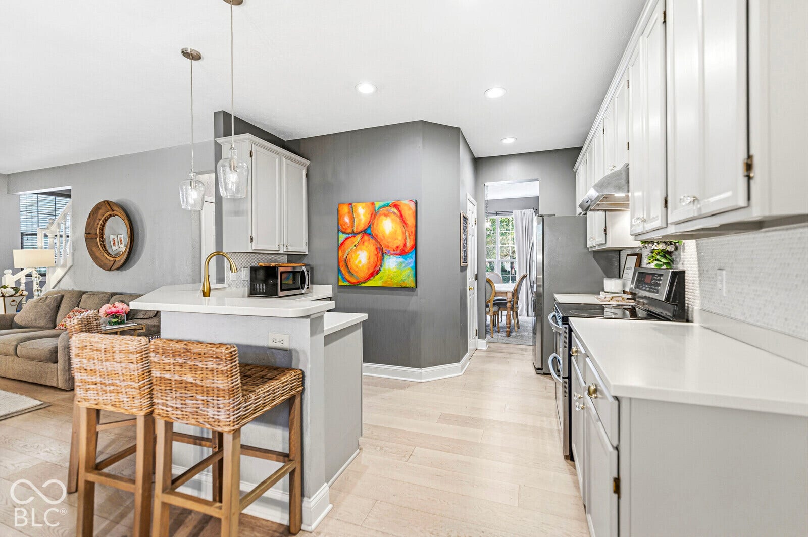 Modern kitchen featuring white cabinetry, light countertops, stainless steel appliances, and wood-finish flooring
