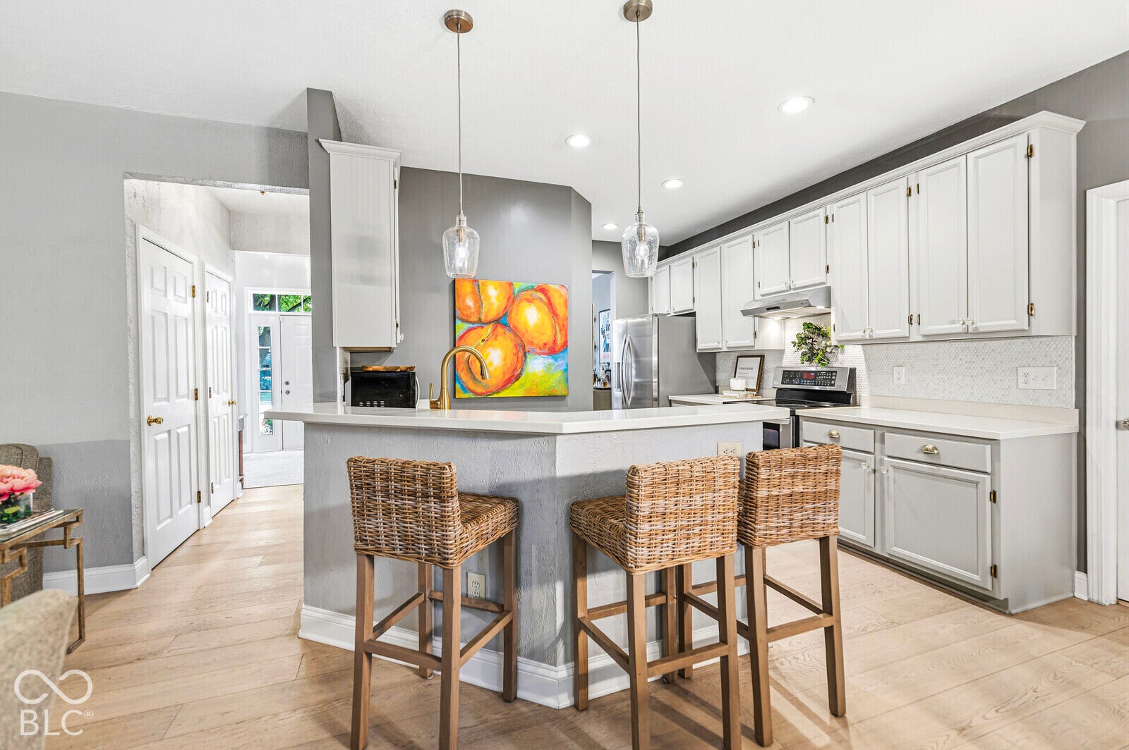 Kitchen featuring light wood-finish flooring, white cabinetry, light countertops, and a built-in breakfast bar with pendant lighting
