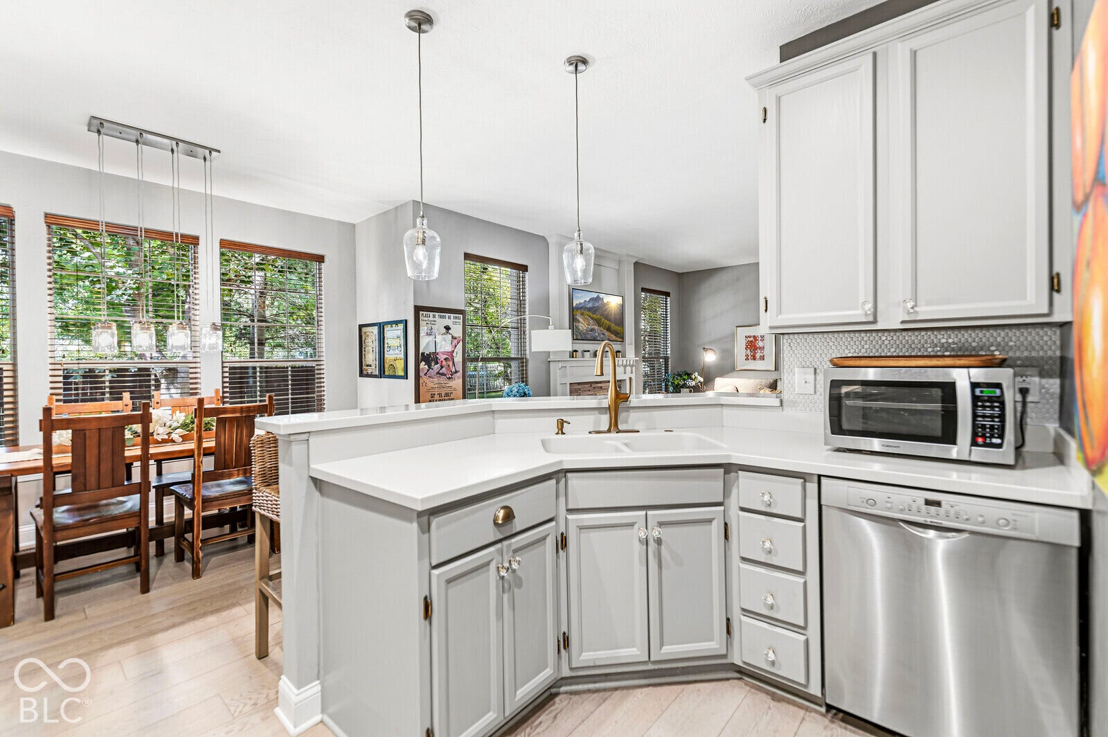 White cabinetry with brushed nickel hardware, stainless steel dishwasher, white countertops, and light wood-finish flooring