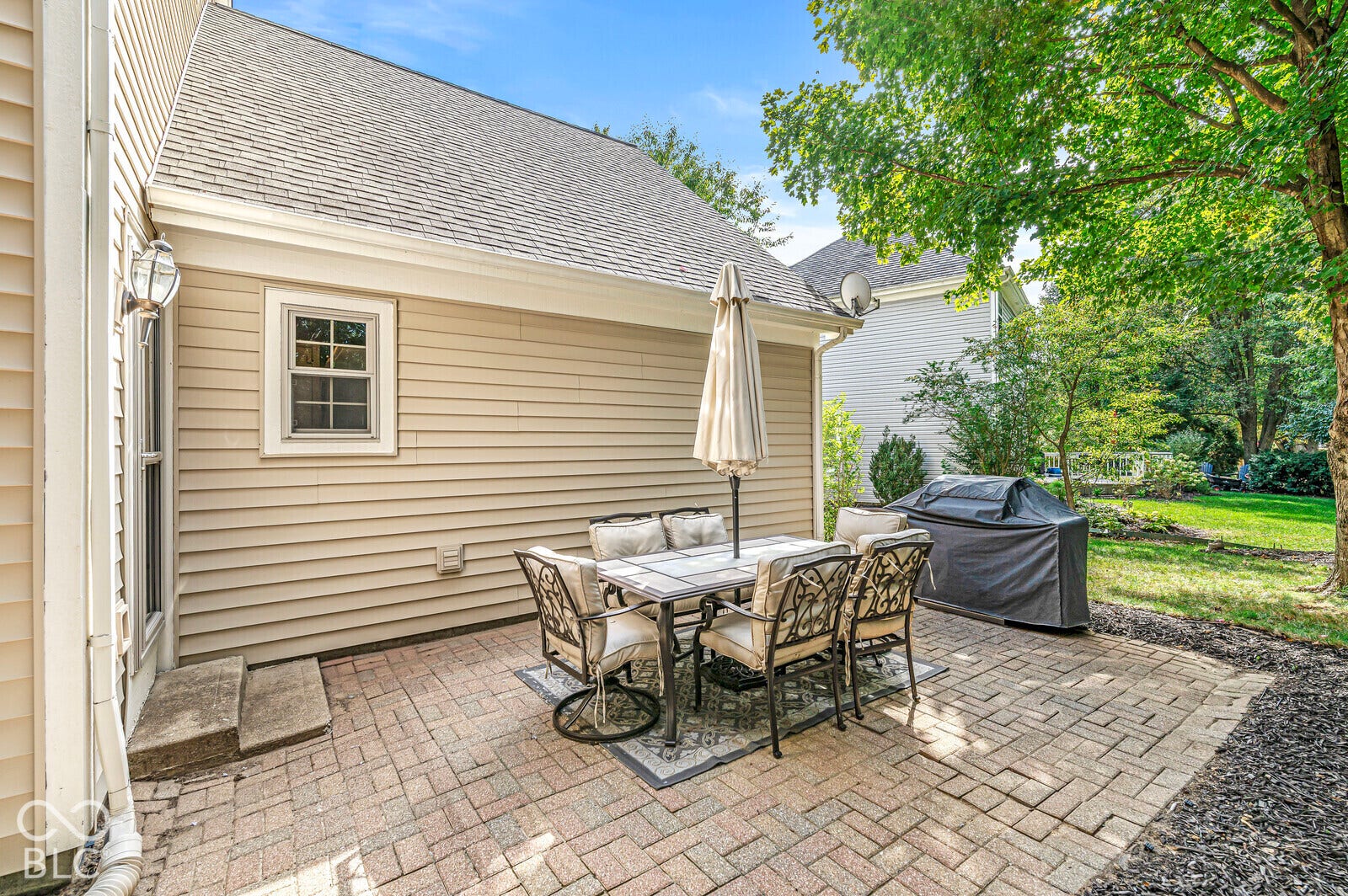 Brick paver patio with a manicured lawn and mature landscaping