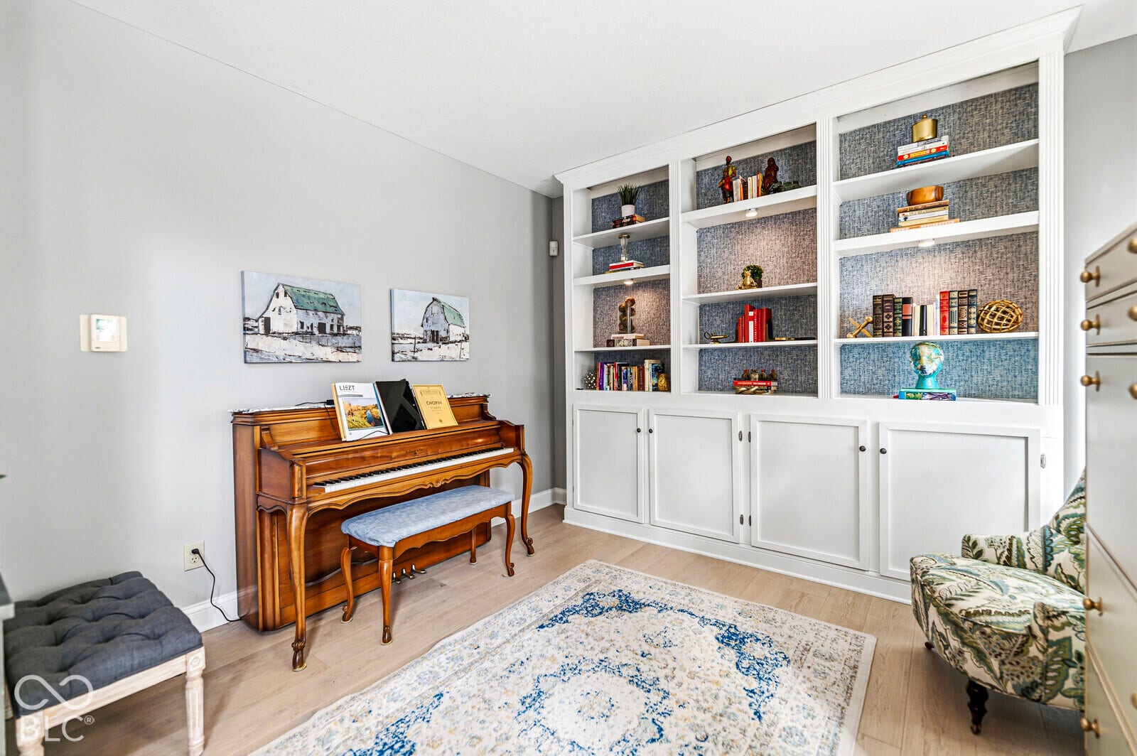 Built-in white shelving with patterned backing, integrated lighting, and lower cabinetry