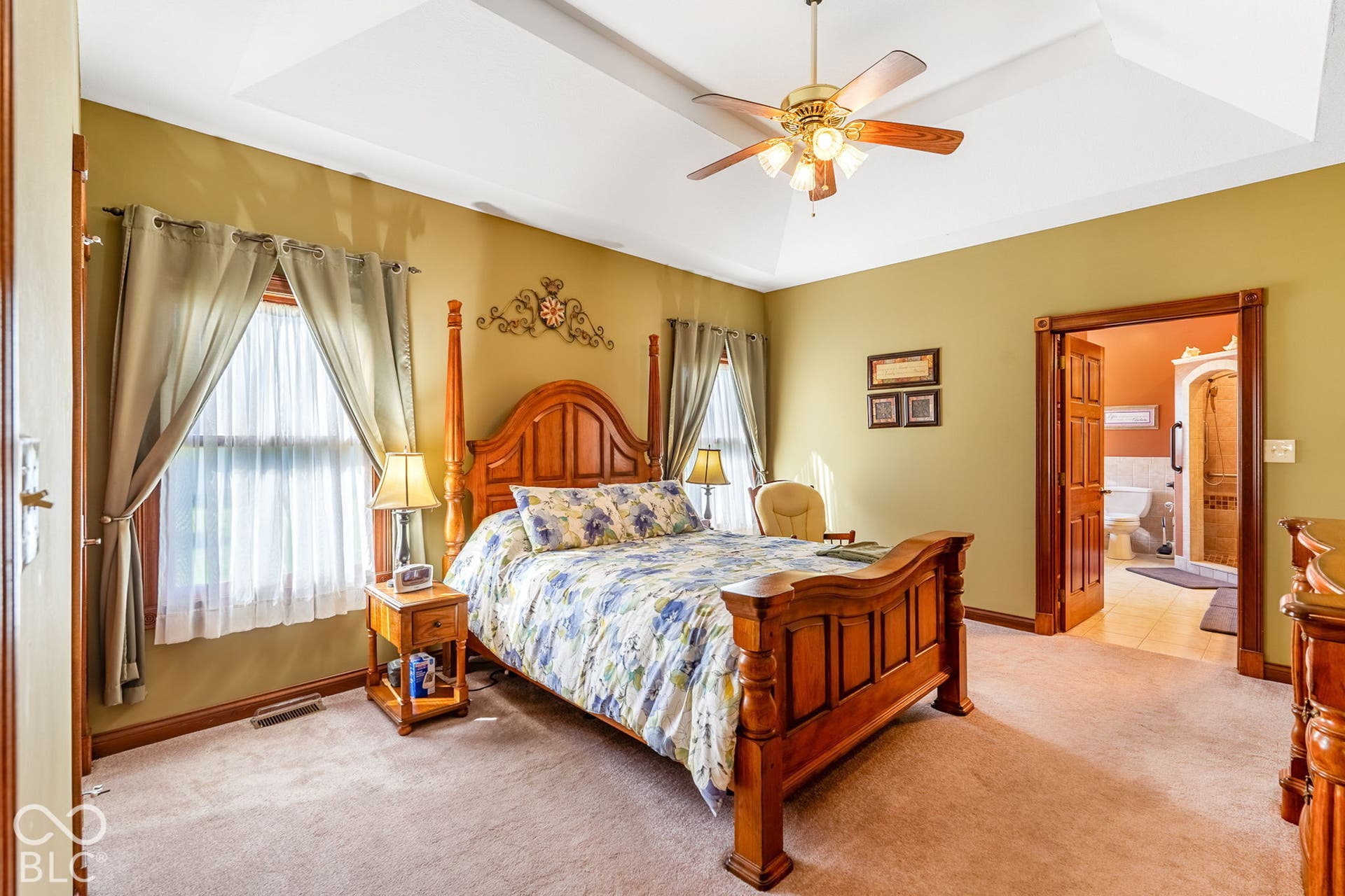 Tray ceiling with a ceiling fan, recessed window, wood-trim doorway, and carpet flooring