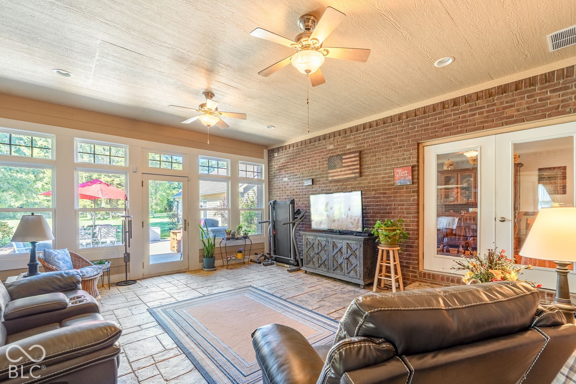 Spacious sunroom featuring exposed brick accents and stone-look tile flooring