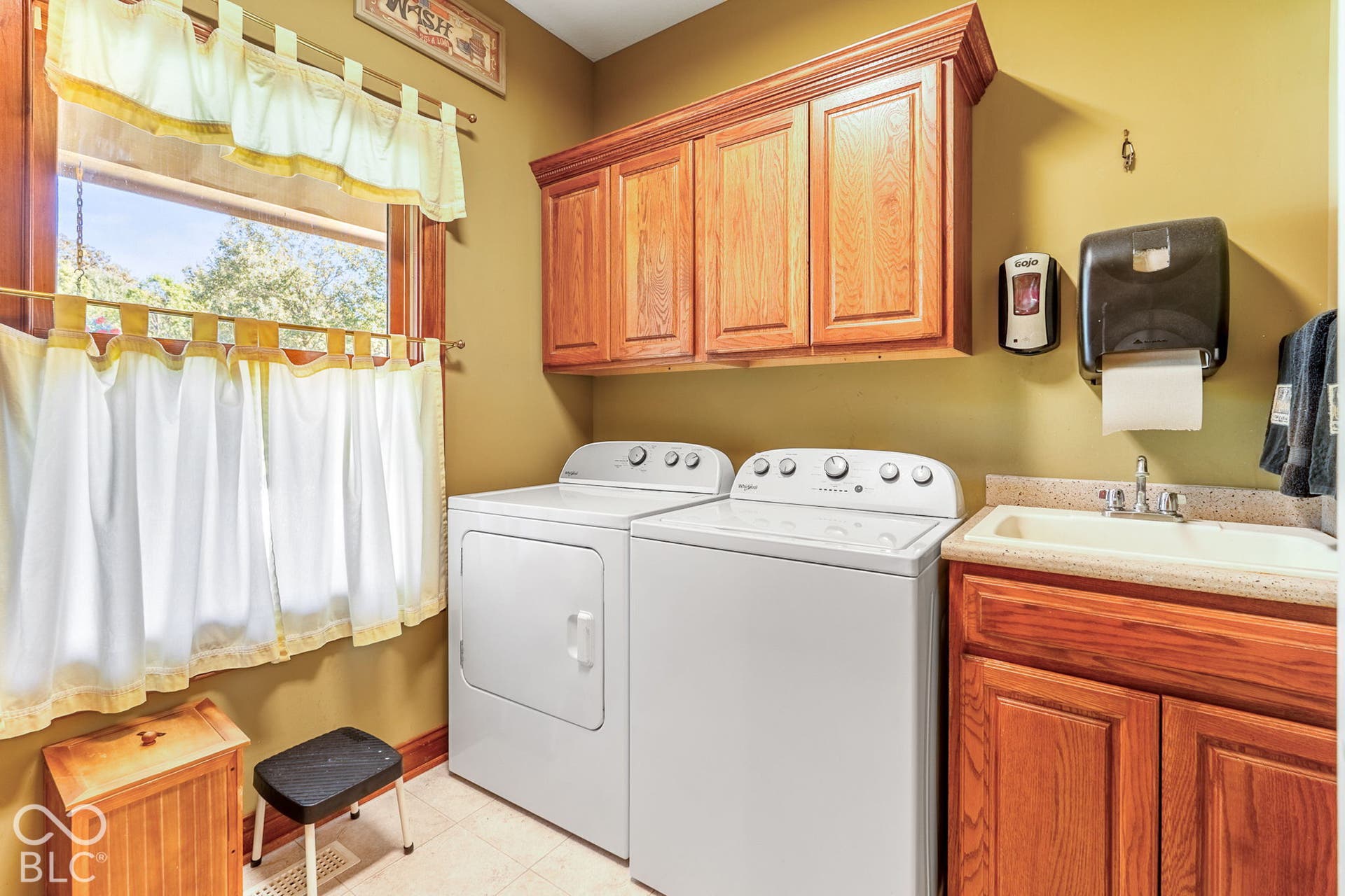 Functional utility space featuring wood-finish cabinetry, a dedicated laundry sink, and a window for natural light