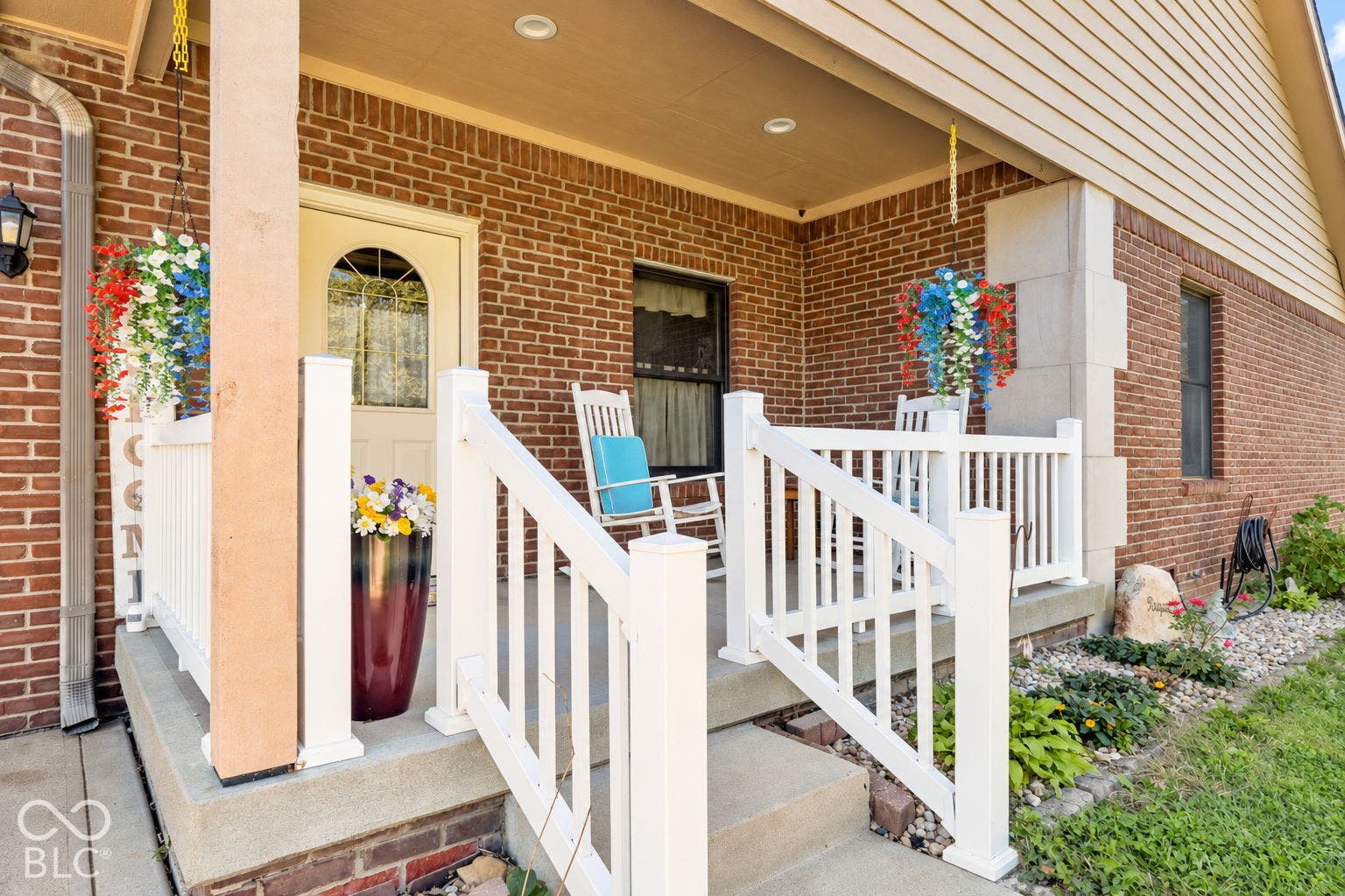 Brick exterior with a covered porch featuring white railing and a concrete entry