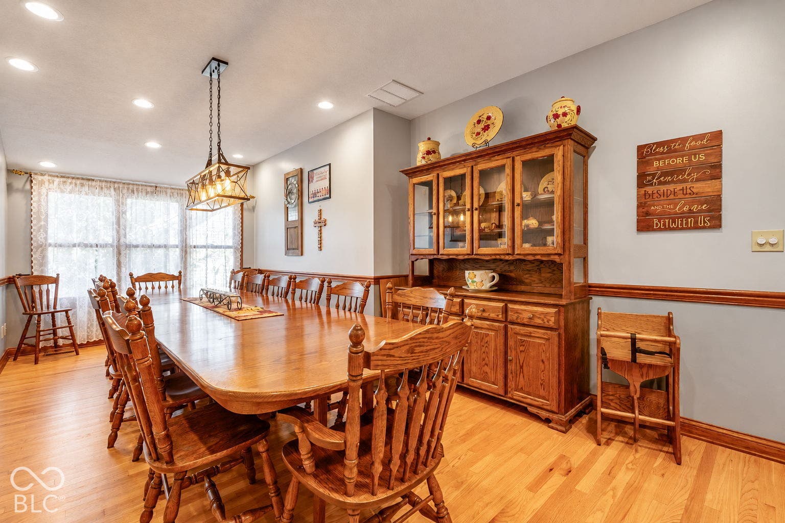 Wood-finish flooring, recessed ceiling lighting, and a multi-pane window with sheer curtains