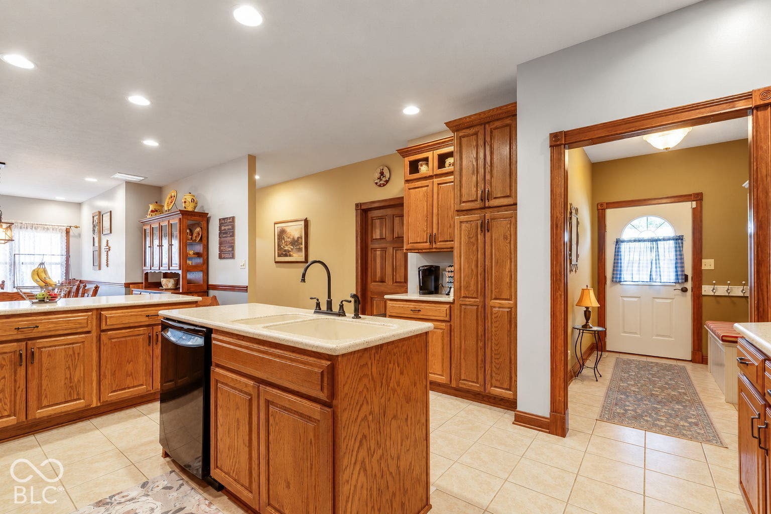 Kitchen featuring an island with an integrated sink, wood-finish cabinetry, tile flooring, and recessed lighting