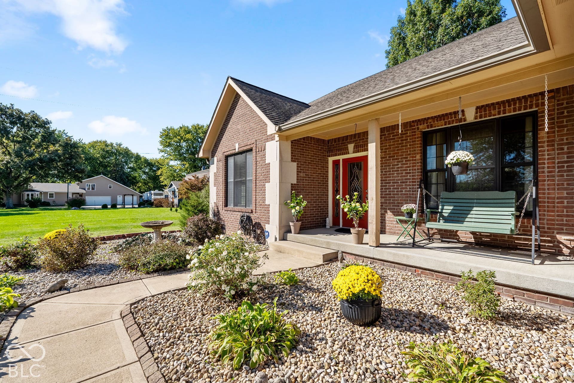 Brick exterior with stone accents, covered front porch, and a red entry door