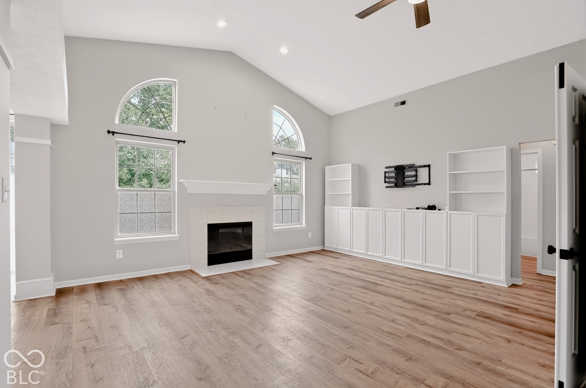 Vaulted ceilings, wood-finish flooring, built-in cabinetry, and a fireplace with a mantel
