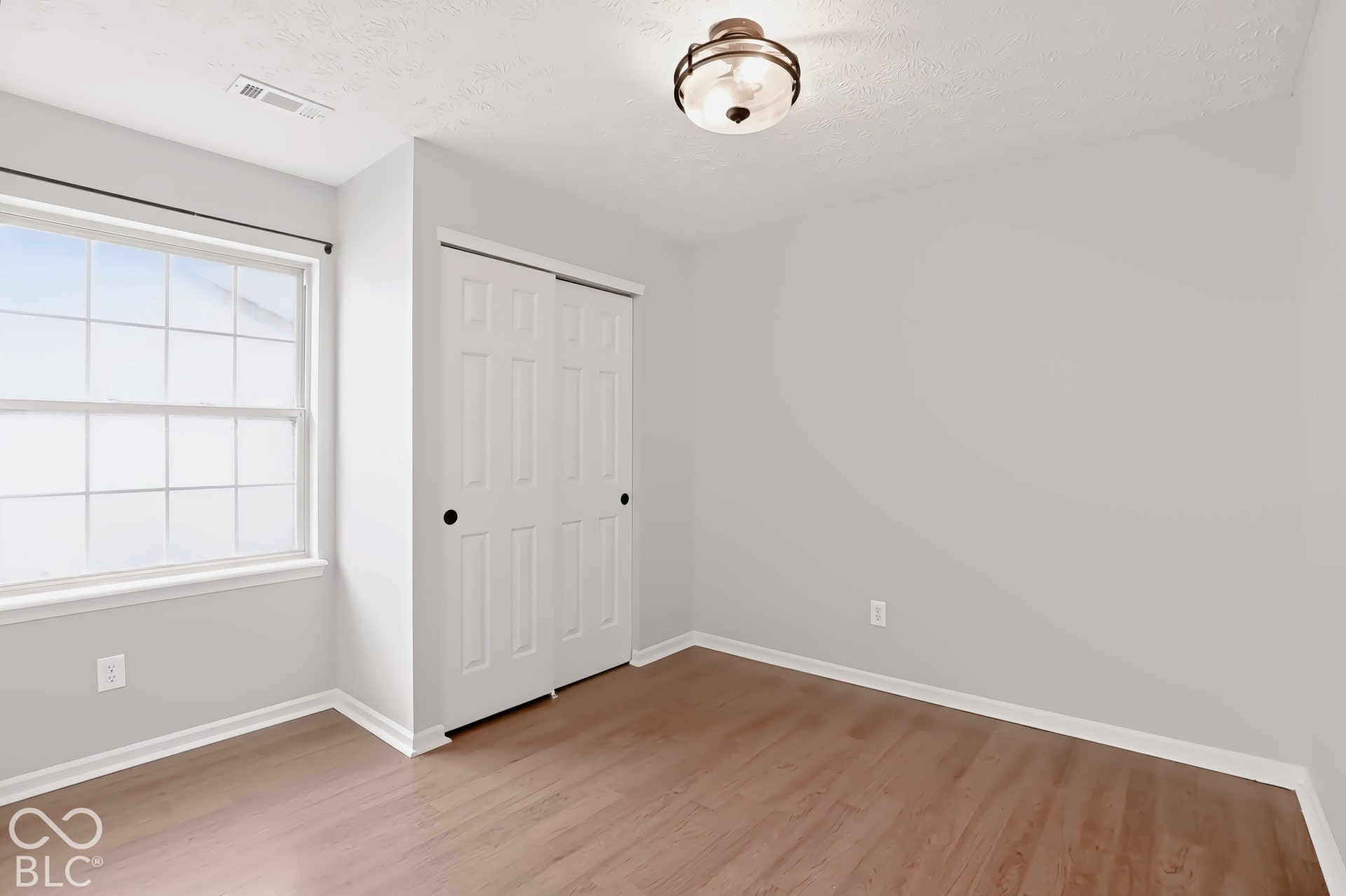 Wood-finish flooring, white trim, and a window with white sashes