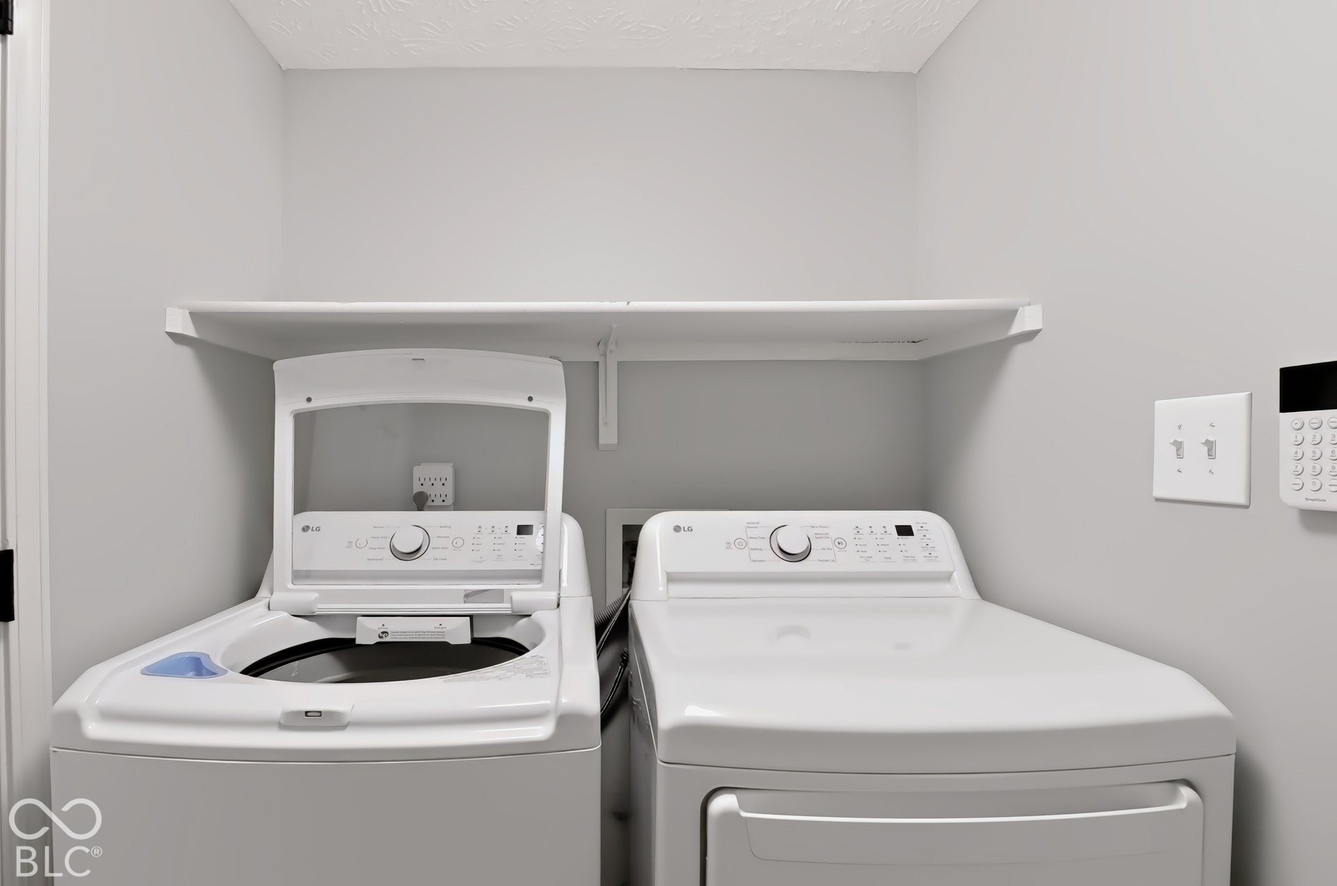 Laundry area with built-in shelving and light gray walls