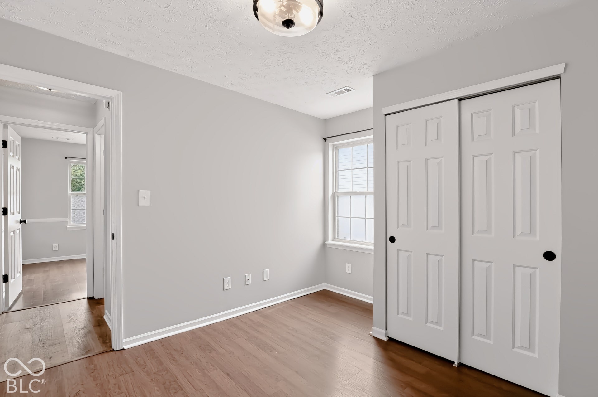 Wood-finish flooring, white paneled doors, sliding closet doors, and recessed window