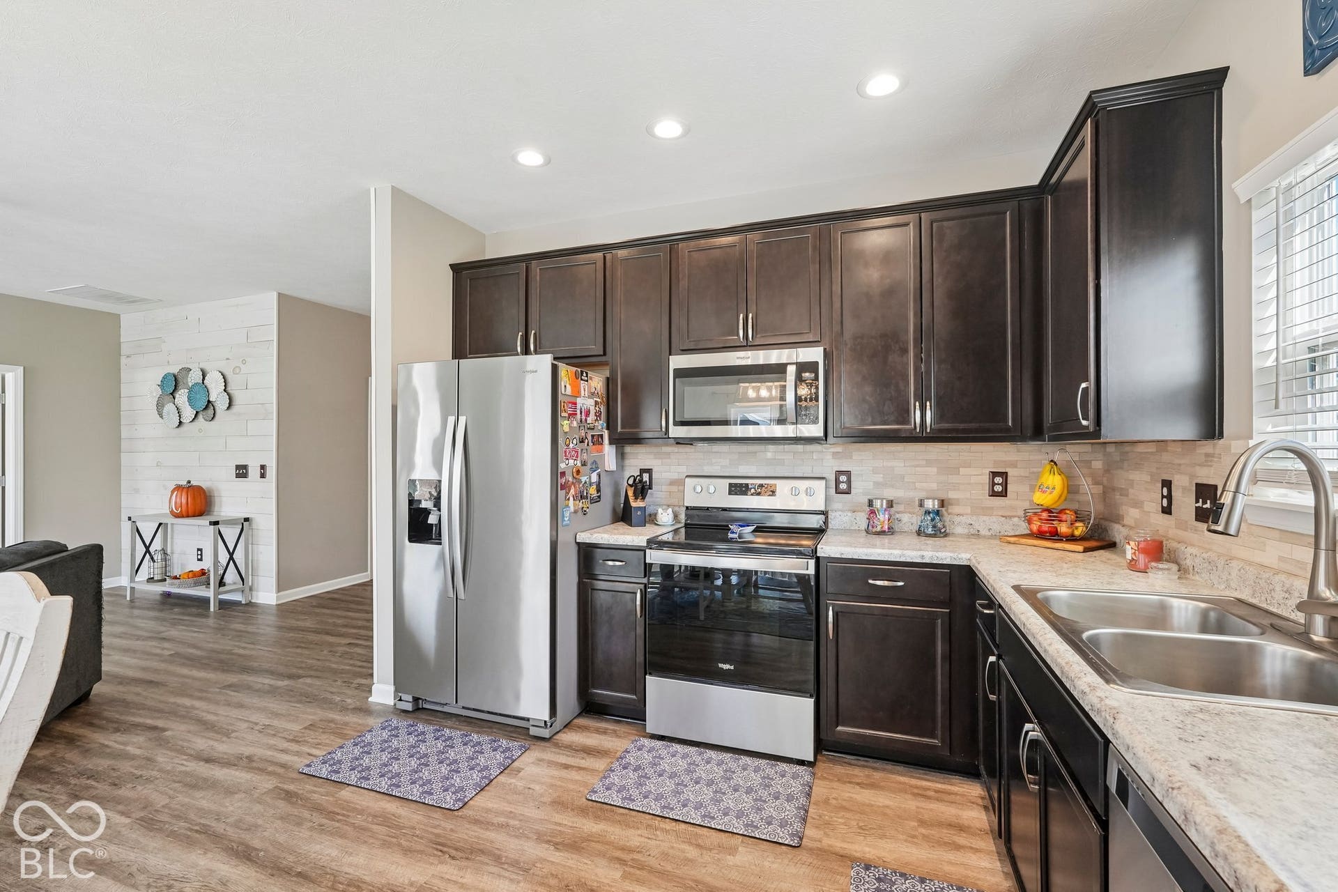 2945 W Calimanco Lane, Monrovia, IN 46157 Kitchen featuring wood-finish flooring, dark wood cabinetry, stainless steel appliances, light-toned countertops, and a tile backsplash