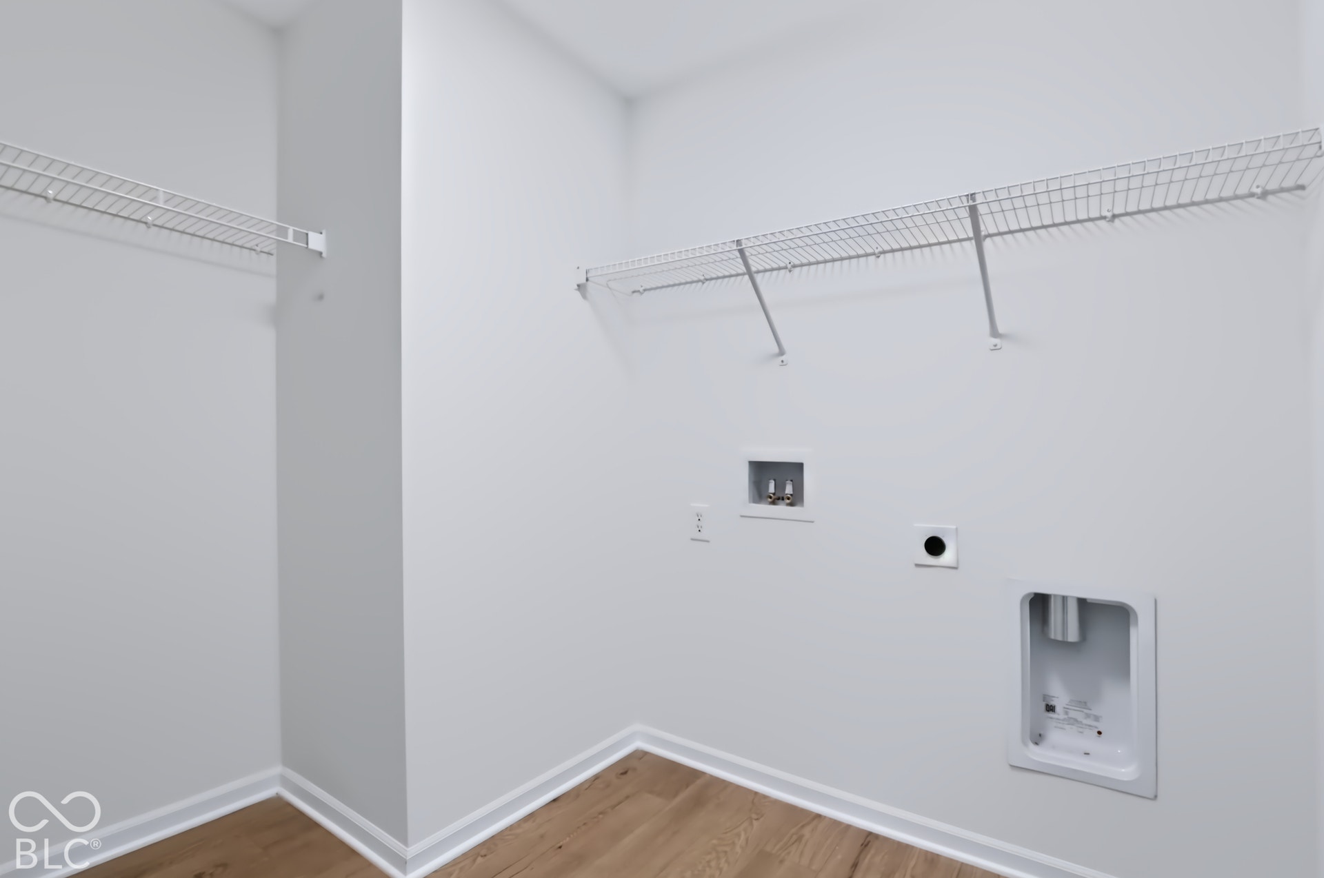 Laundry area with wood-finish flooring, wire shelving, and utility hookups