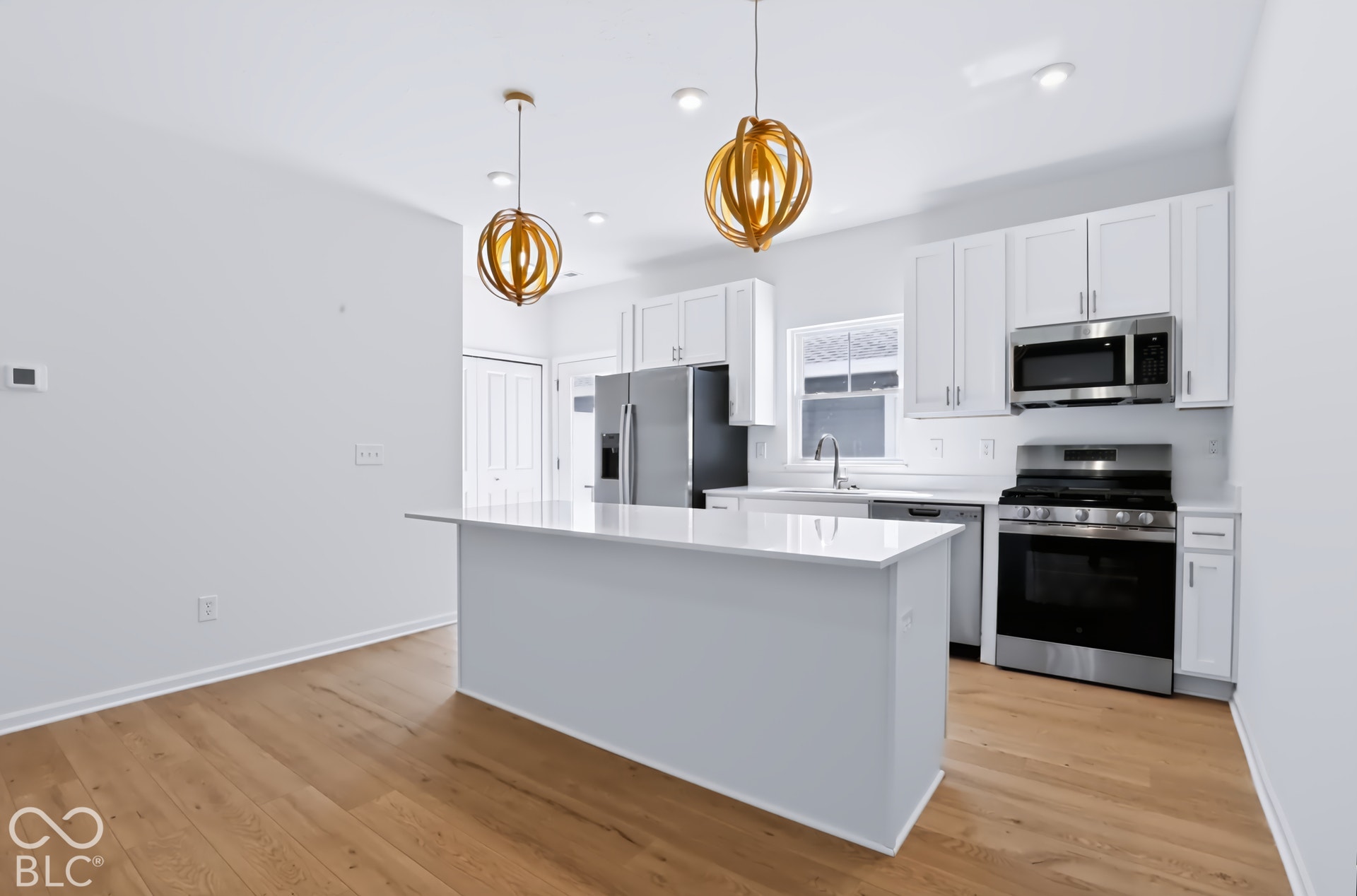 Kitchen featuring a center island, stainless steel appliances, white cabinetry, recessed lighting, and wood-finish flooring
