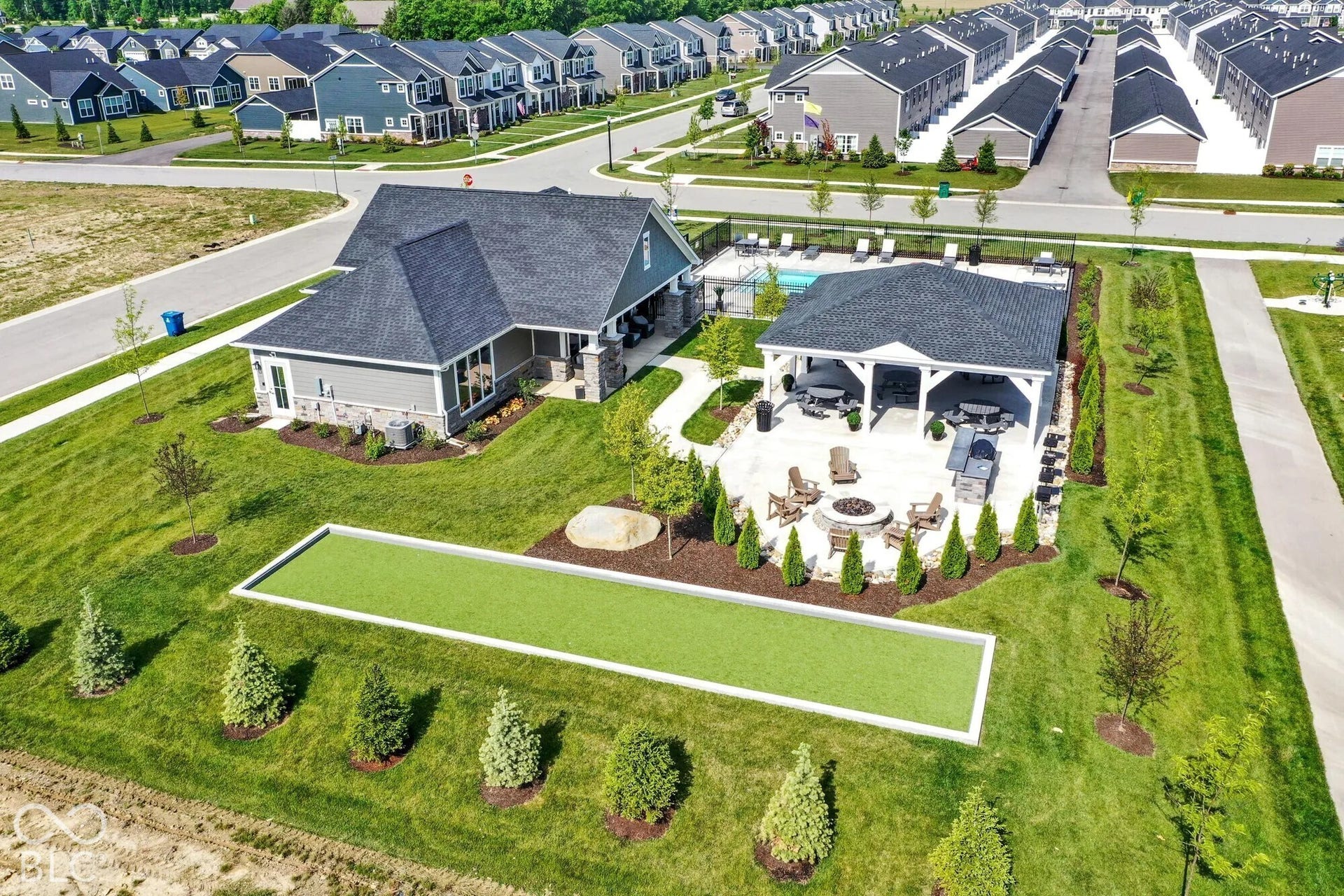 Community clubhouse with covered patio, outdoor swimming pool, and bocce ball court