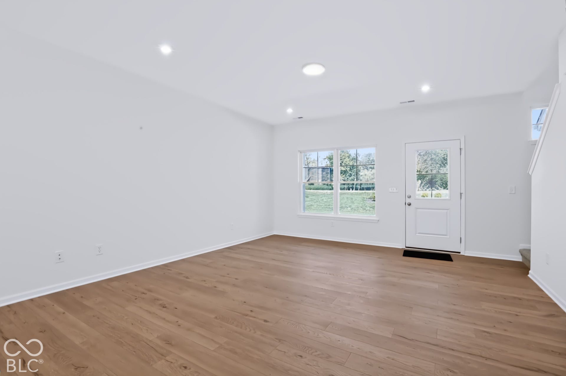 Recessed ceiling lighting, durable wood-finish flooring, white walls, white trim, and a window with exterior views