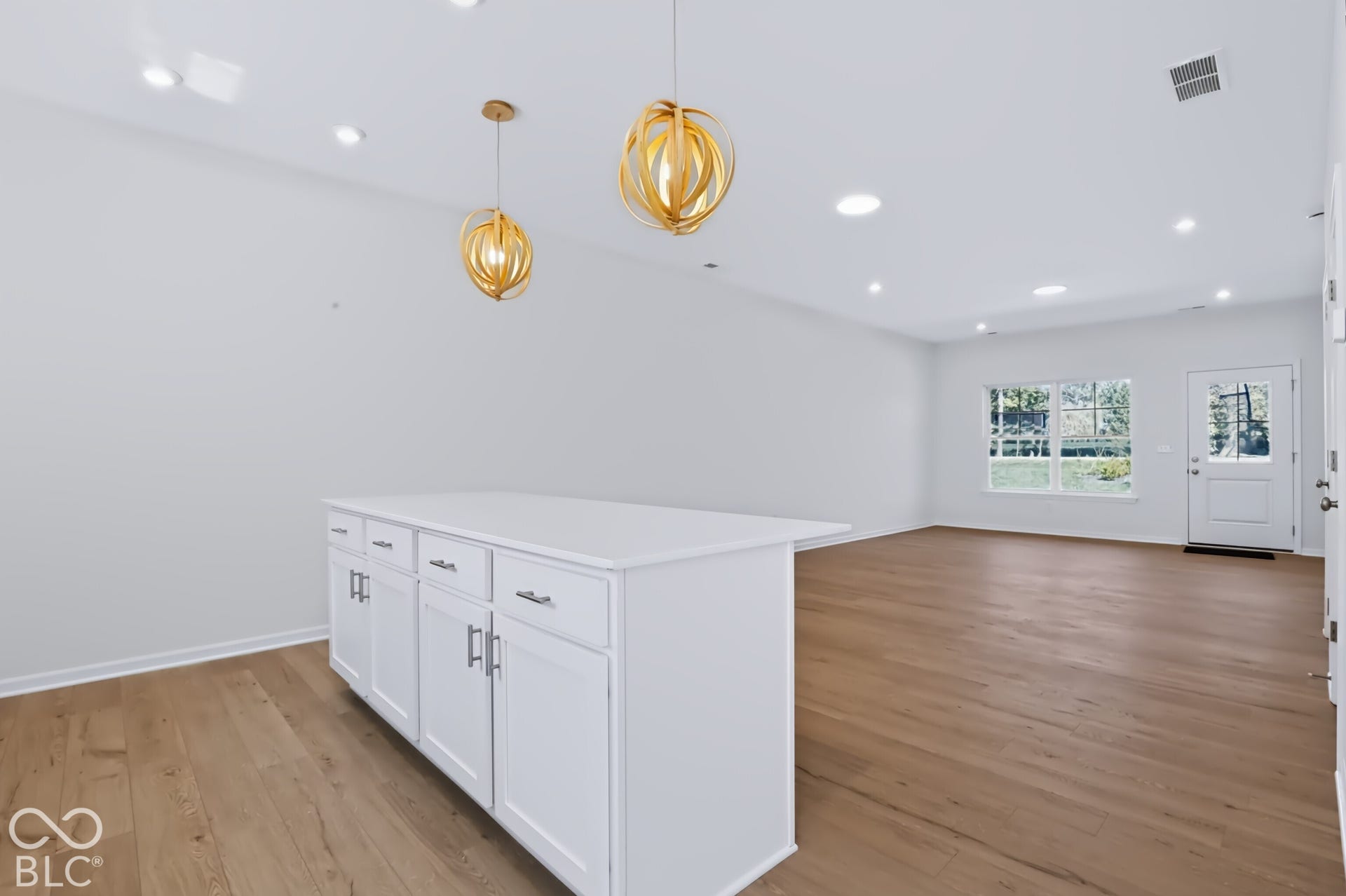 White kitchen island with a solid surface countertop, wood-finish flooring, recessed lighting, and contemporary pendant light fixtures