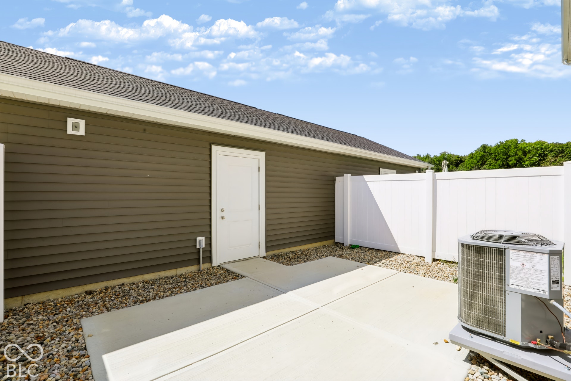 Concrete patio surface and walkway, enclosed by a white privacy fence