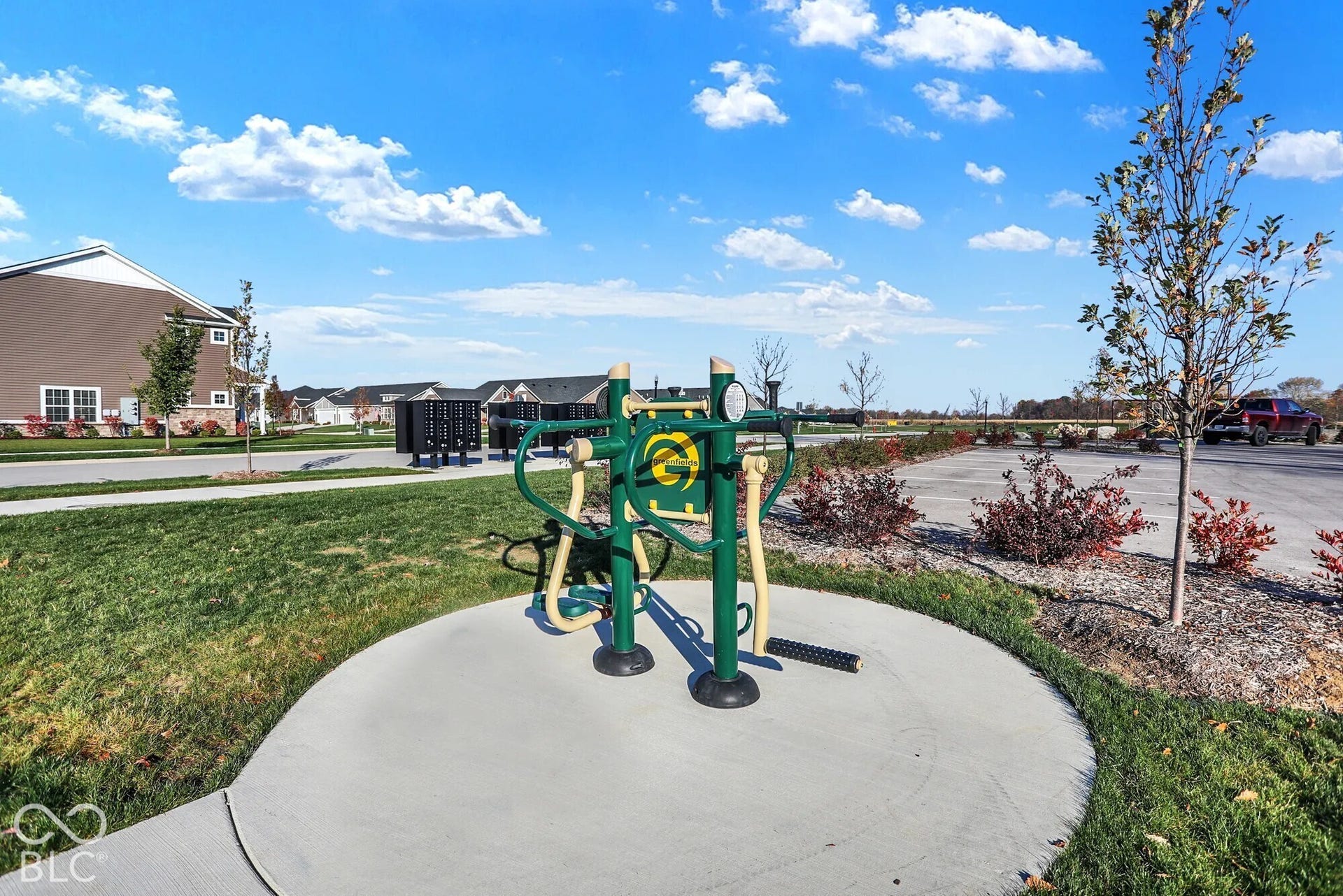 Outdoor fitness equipment on a concrete pad with a surrounding grassy area