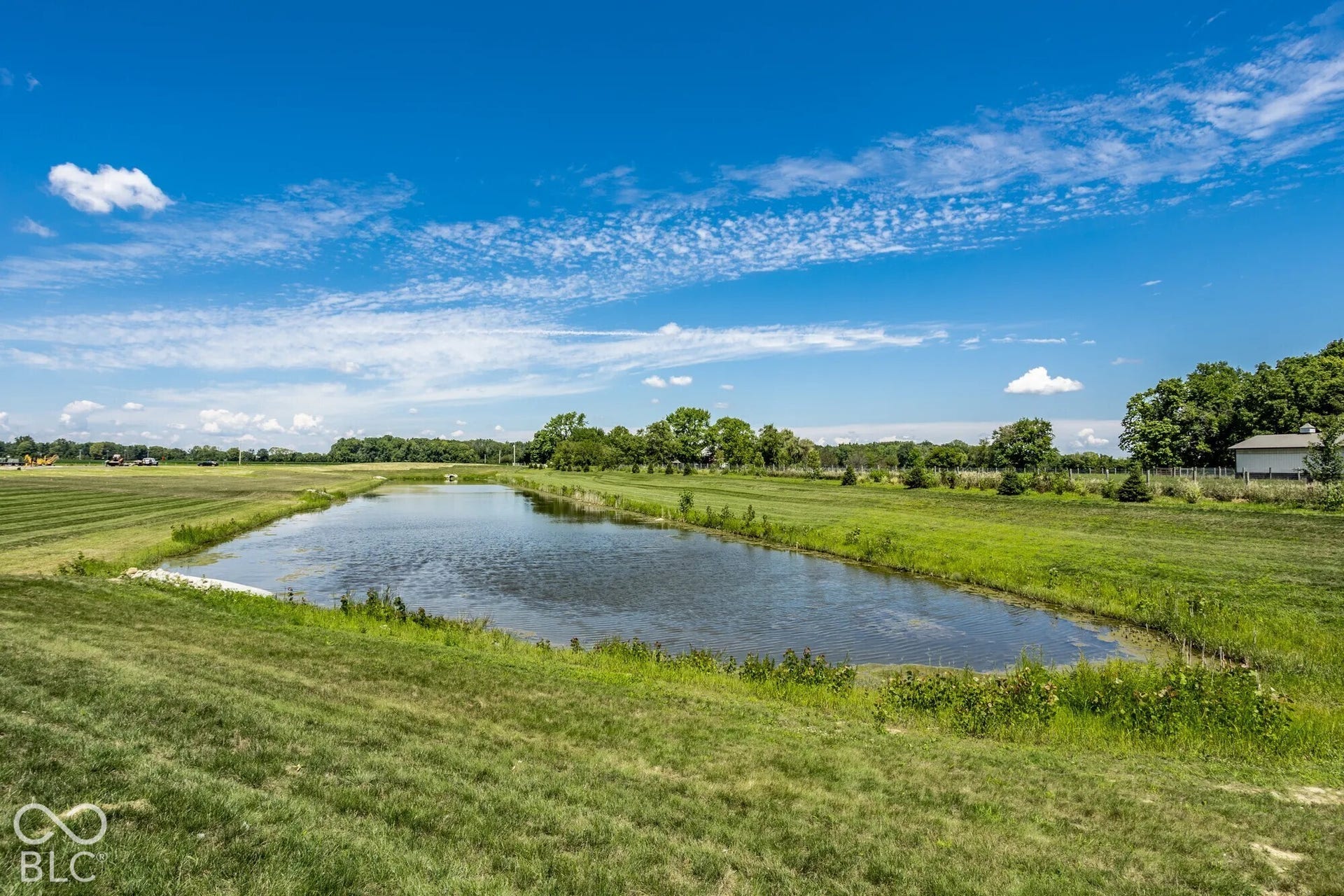 Expansive grounds featuring a pond, manicured lawn, and mature trees