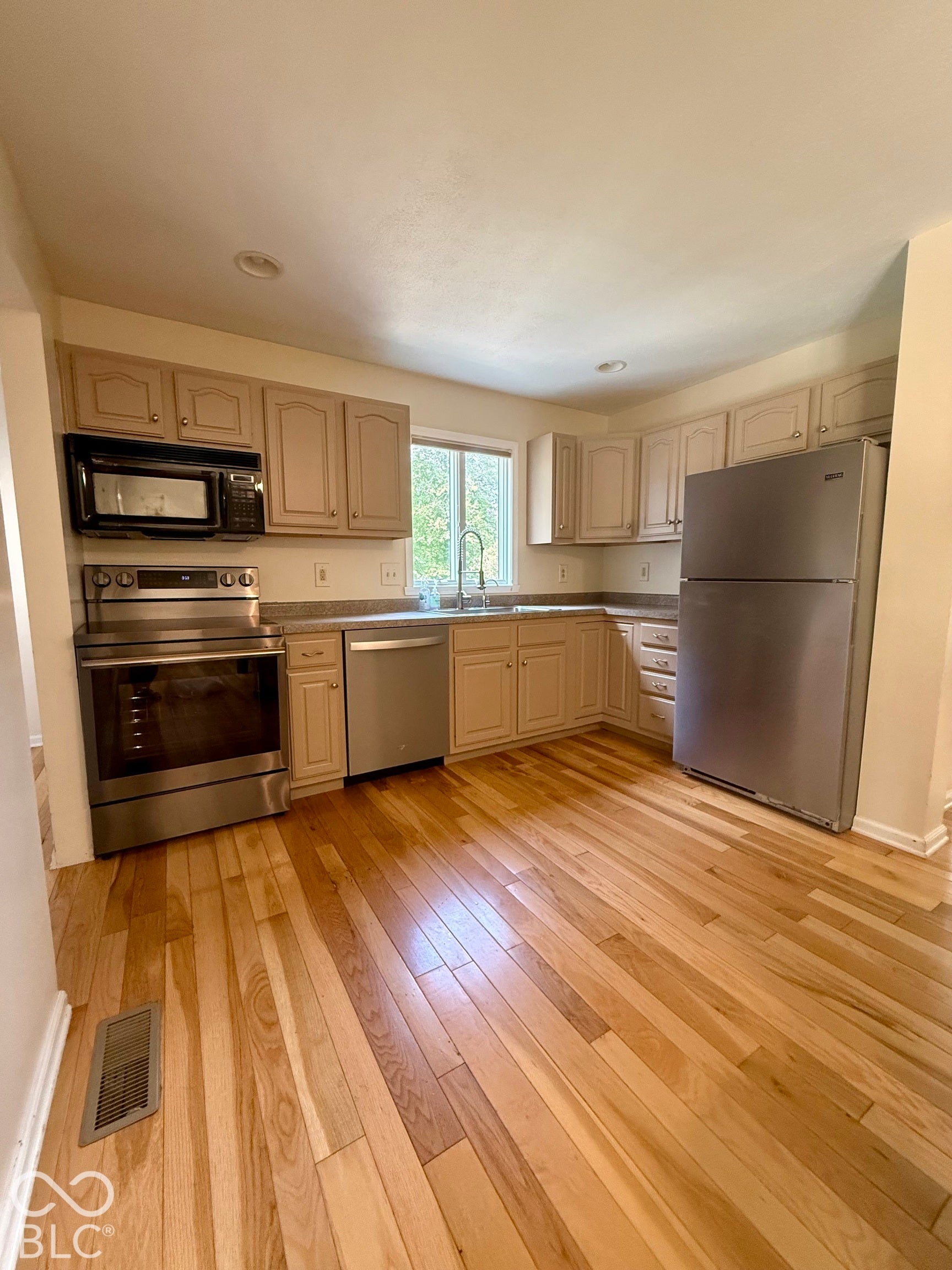 Kitchen featuring wood-finish flooring, stainless steel appliances, recessed lighting, ample cabinetry, and a window above the sink