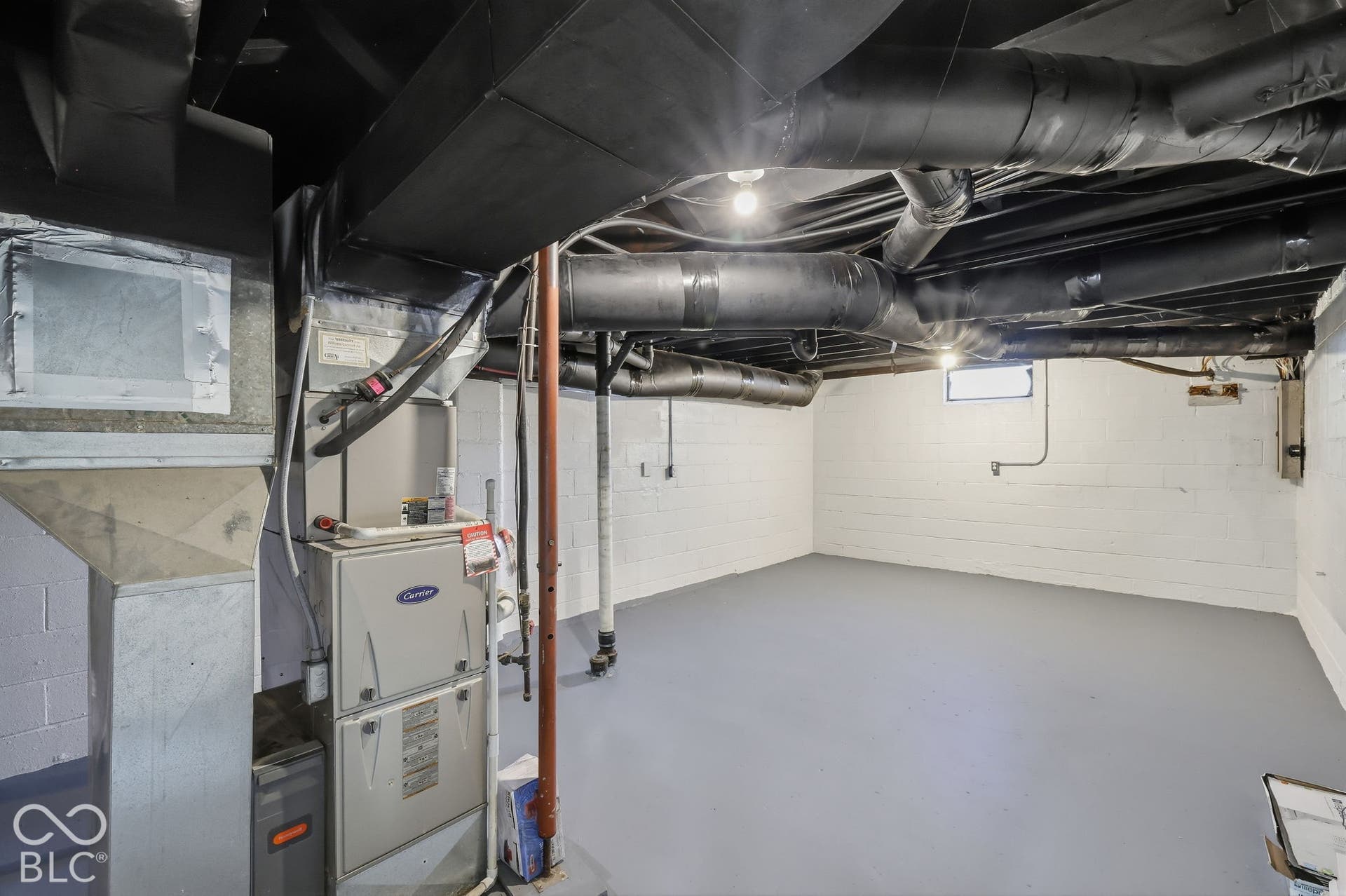 Painted concrete block walls and floor, exposed ceiling with painted ductwork, and a built-in window