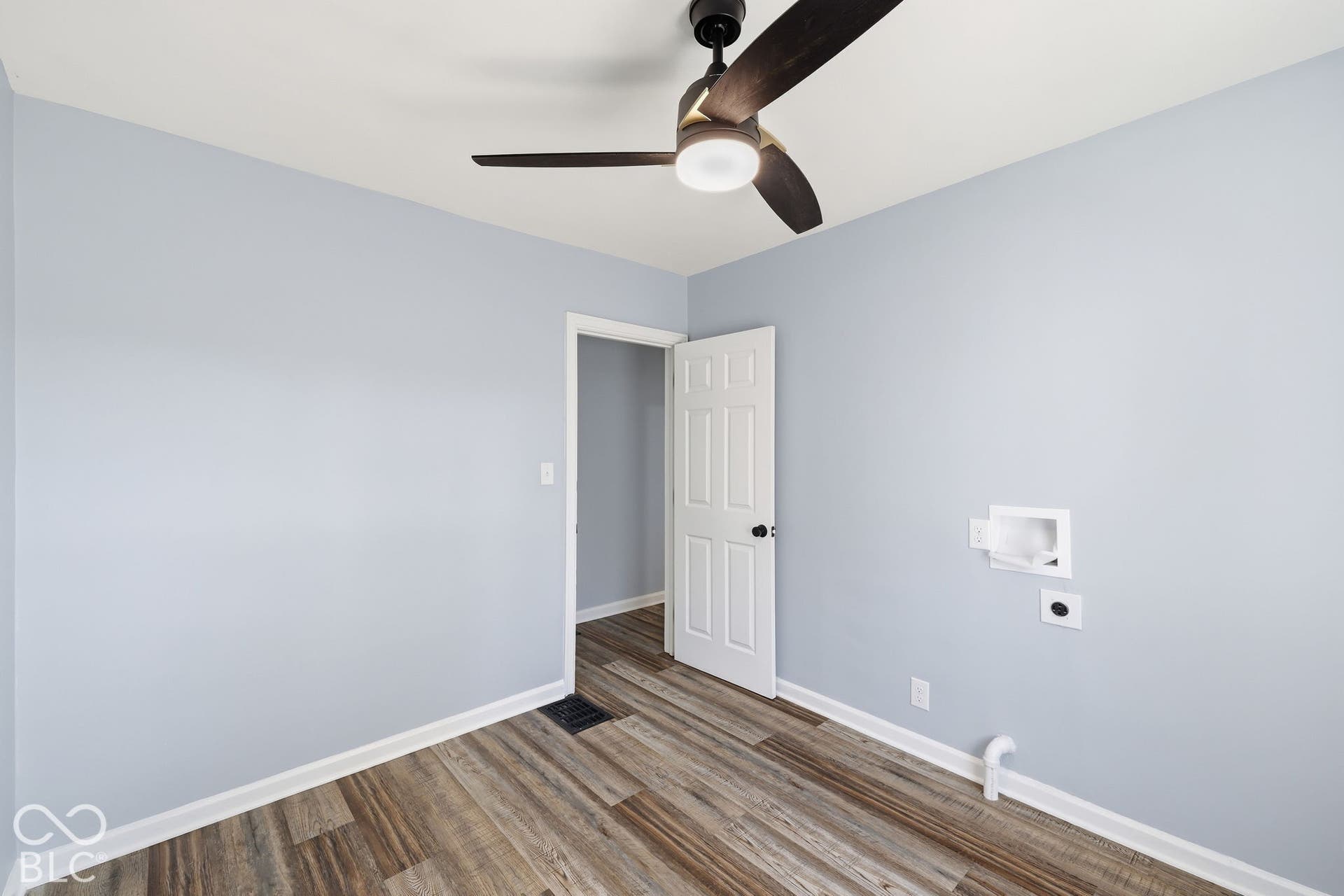 Wood-finish flooring with light blue walls, a contemporary ceiling fan, and a white paneled door
