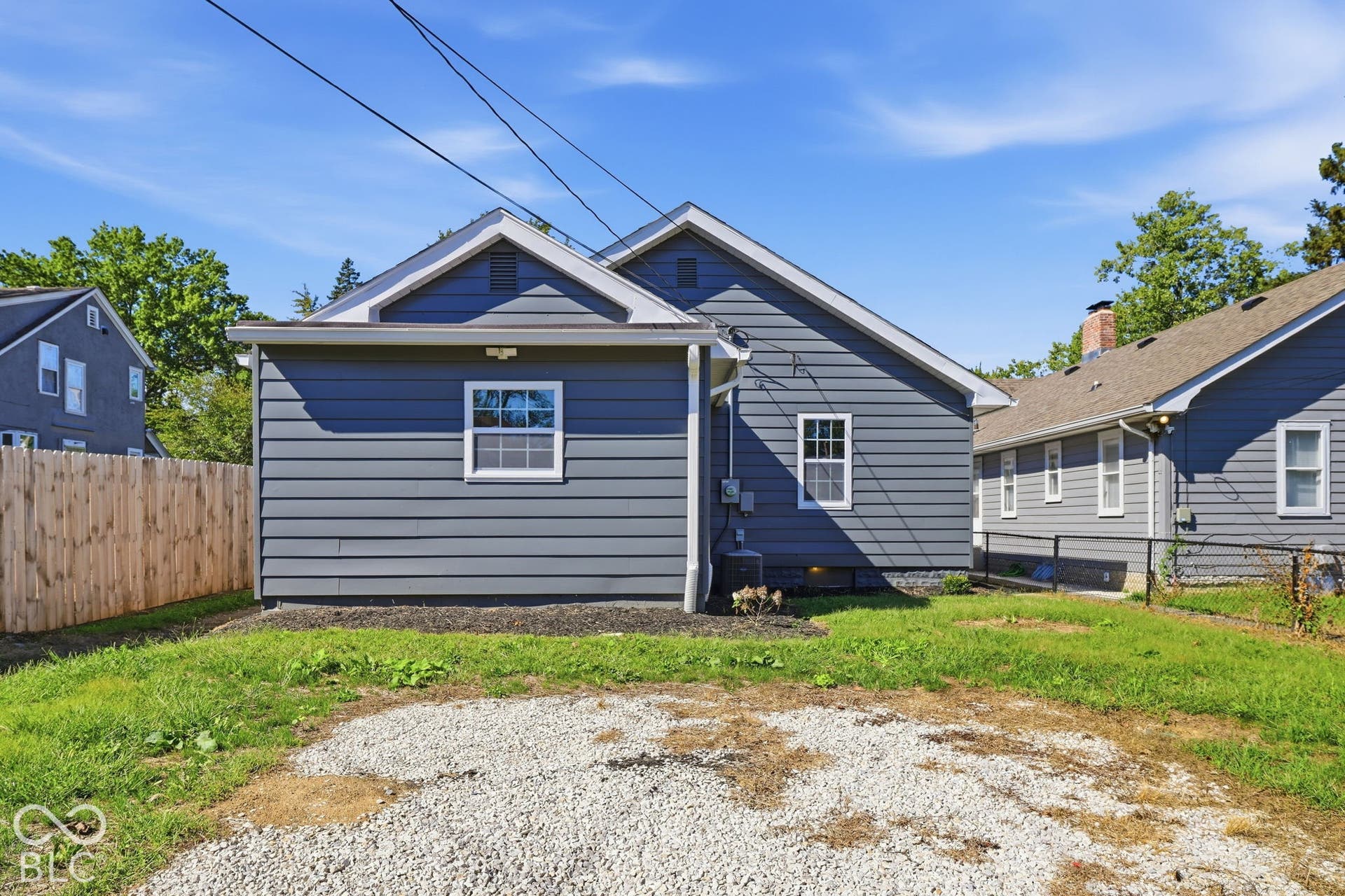 Gray horizontal siding, white trim, white-framed windows, and a light wooden fence