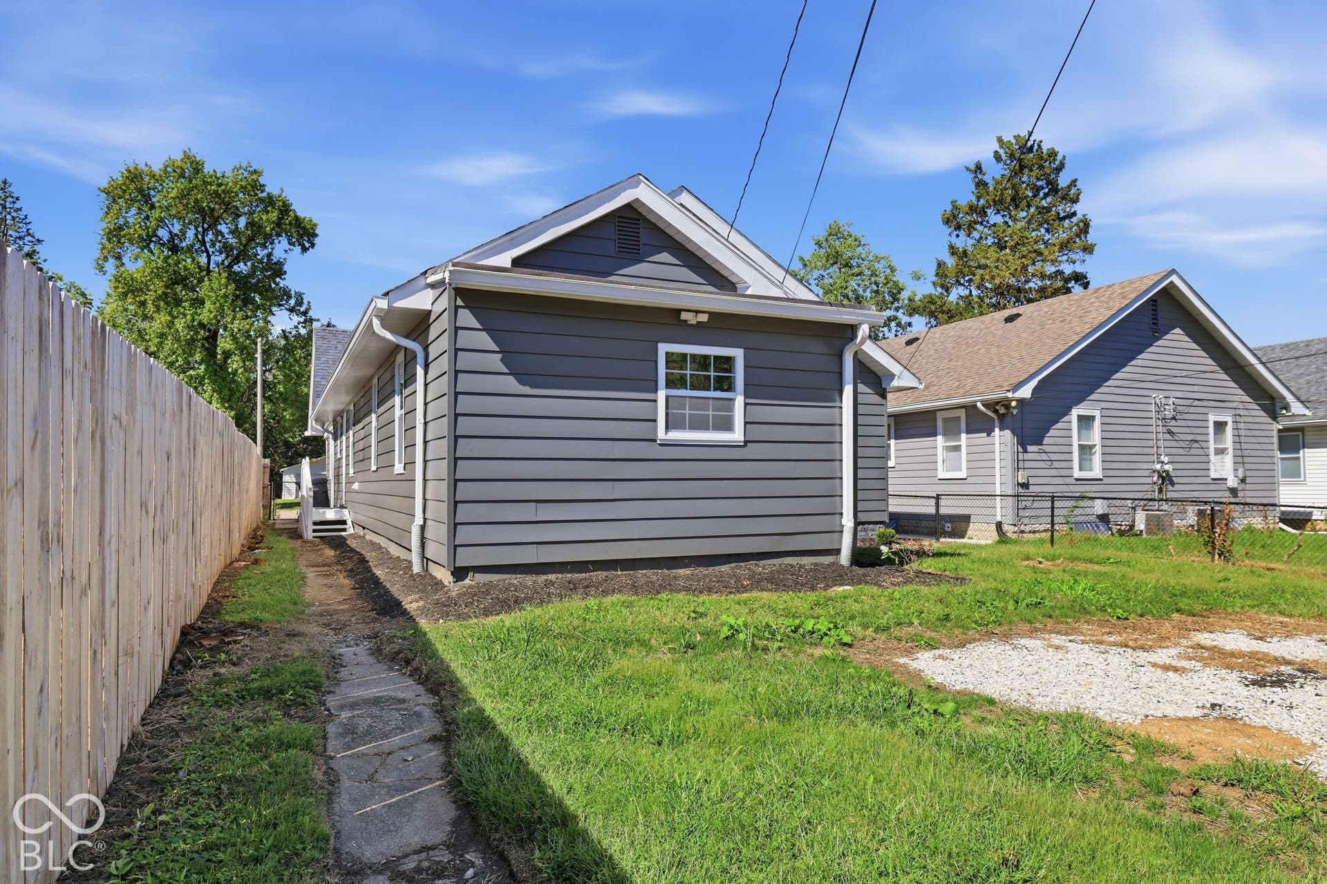 Grey horizontal siding exterior with white trim, a gabled roof, and a wood privacy fence